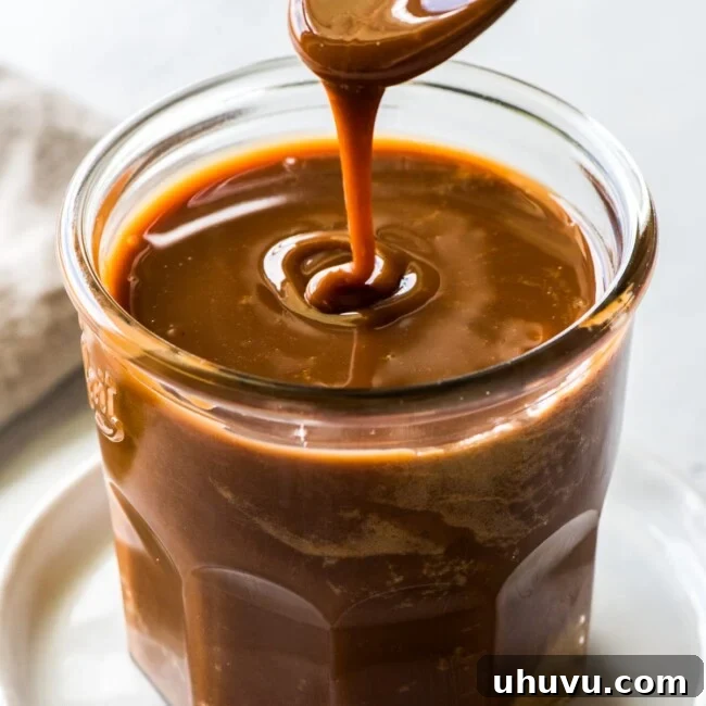 Cajeta pouring from a spoon into a glass jar.