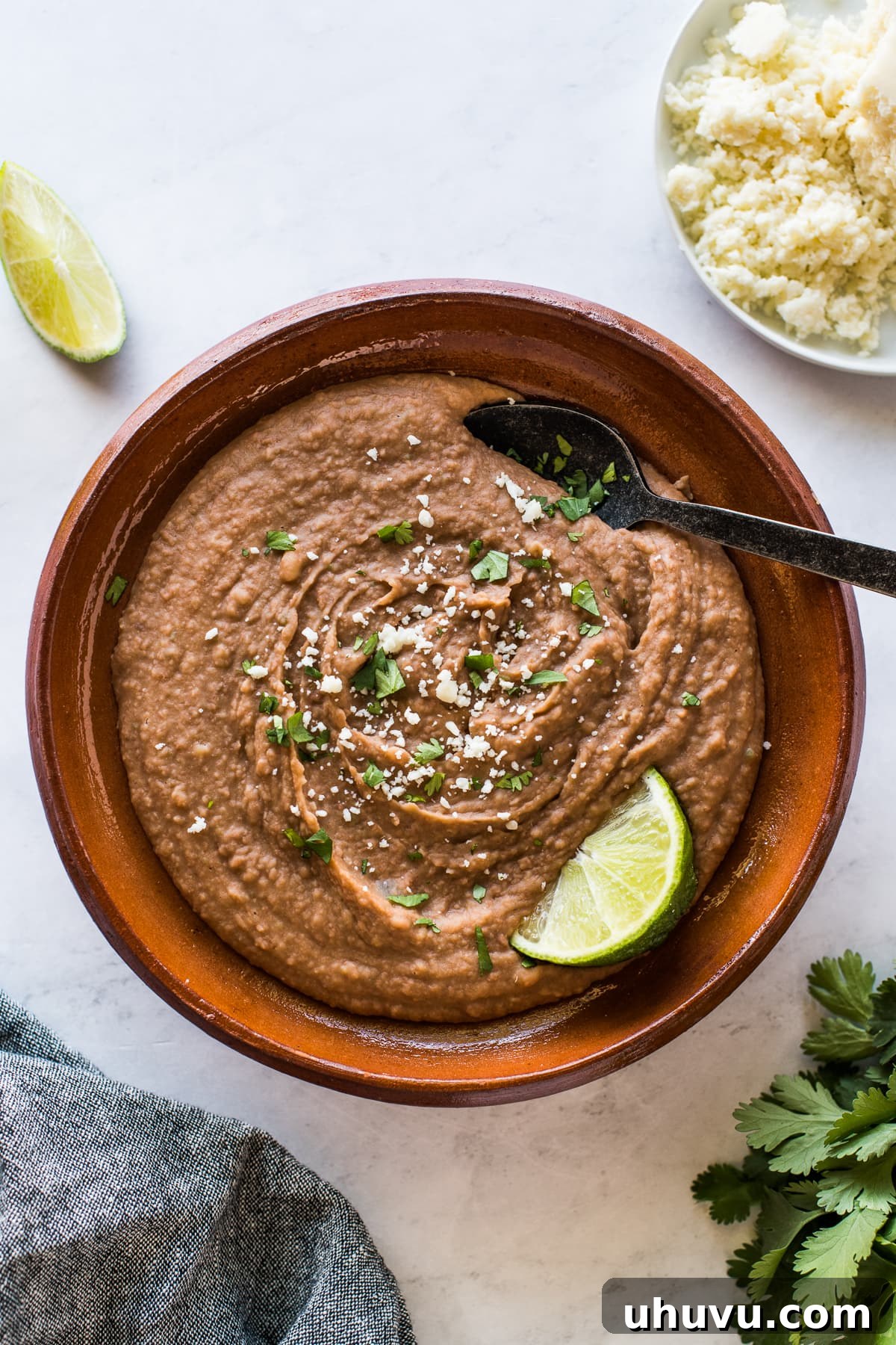 Quick and Creamy Instant Pot Refried Beans 2 Instant Pot refried beans in a bowl topped with cilantro and cotija cheese.