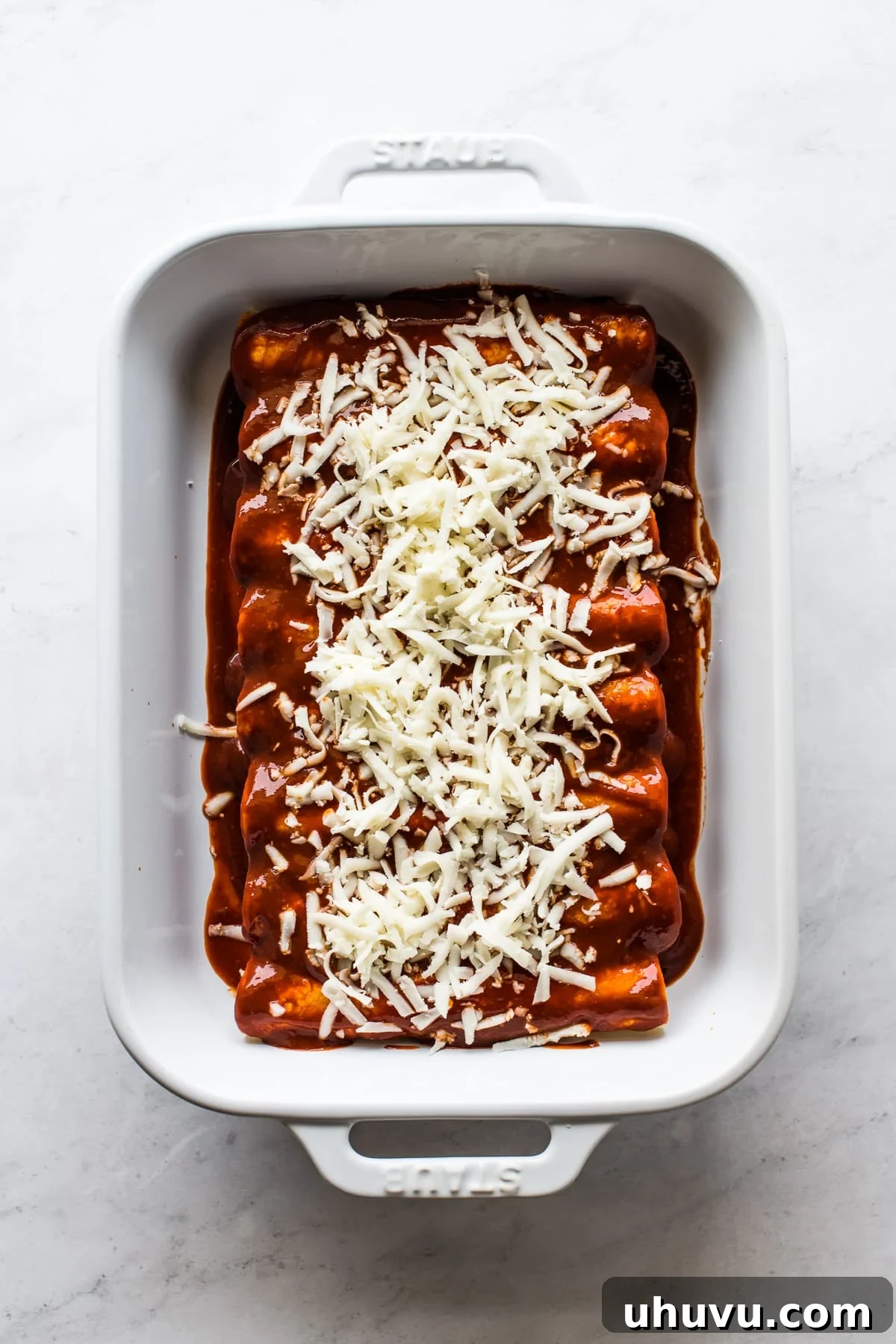 Gooey Cheese Enchiladas 5 A baking dish with cheese enchiladas topped with more shredded cheese.