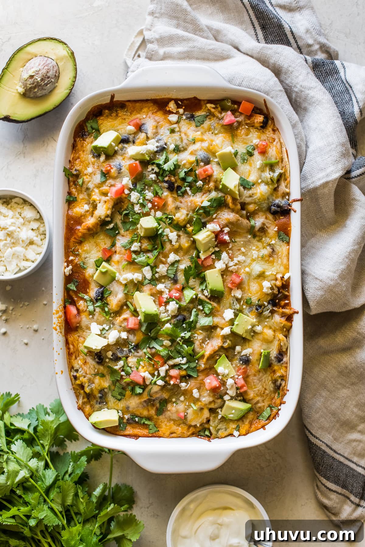 Ultimate Cheesy Chicken Enchilada Bake 2 Chicken enchilada casserole topped with cilantro, diced tomatoes, and avocados.
