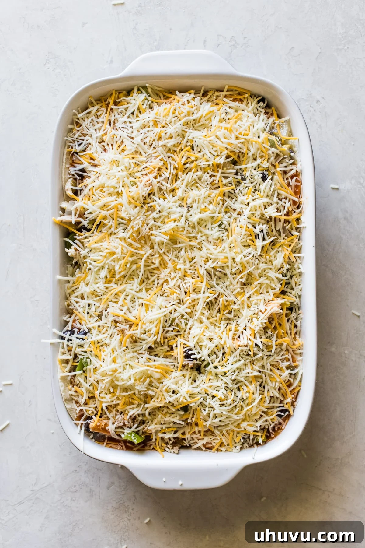 Ultimate Cheesy Chicken Enchilada Bake 3 Shredded cheese on top of chicken enchilada casserole before baking.
