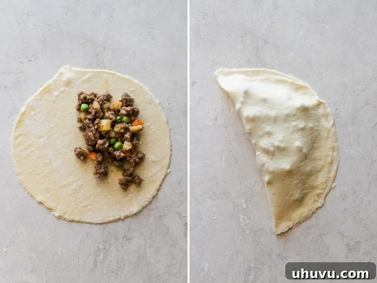 A generous scoop of ground beef filling placed on one half of an empanada dough disc.