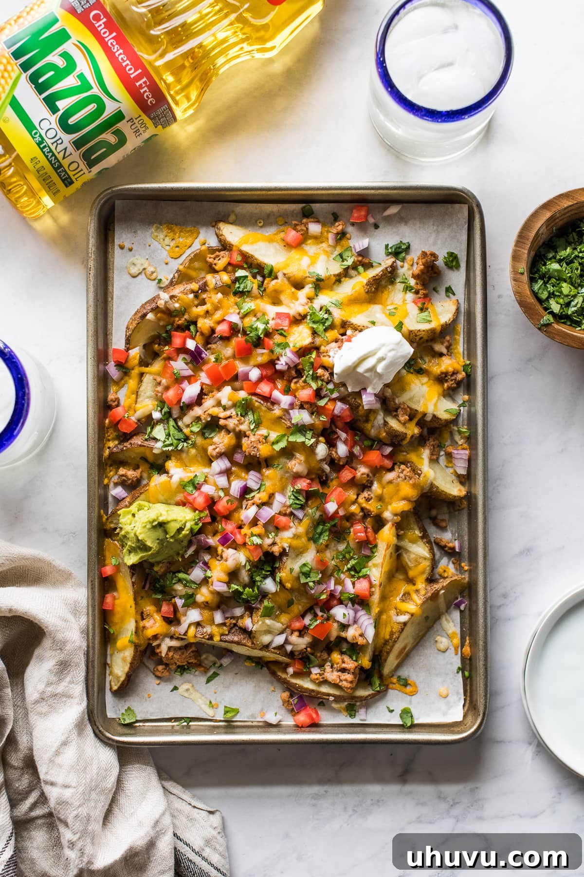 Loaded Nacho Potato Wedges 2 Baked potato wedges topped with melted cheese on a baking sheet.