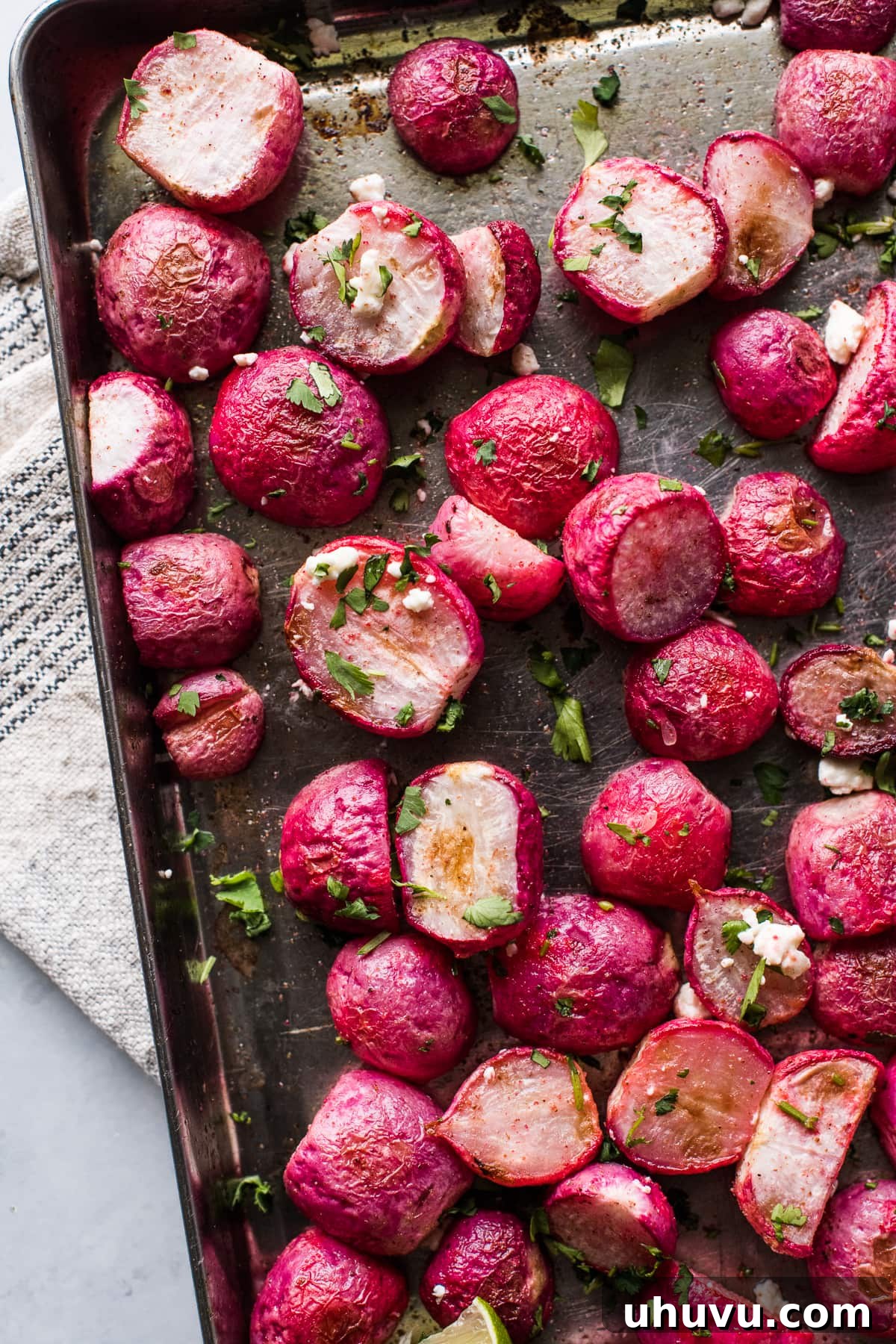 Roasted radishes topped with lime juice, cilantro, and cotija or feta cheese, presenting a vibrant and inviting dish.