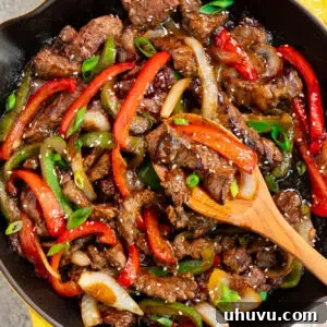 Sizzling Beef and Peppers 13 pepper steak in a skillet with a wooden spoon