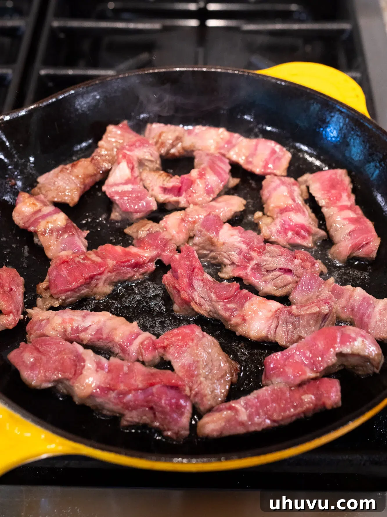 Sliced flank steak cooking in a hot skillet for stir fry