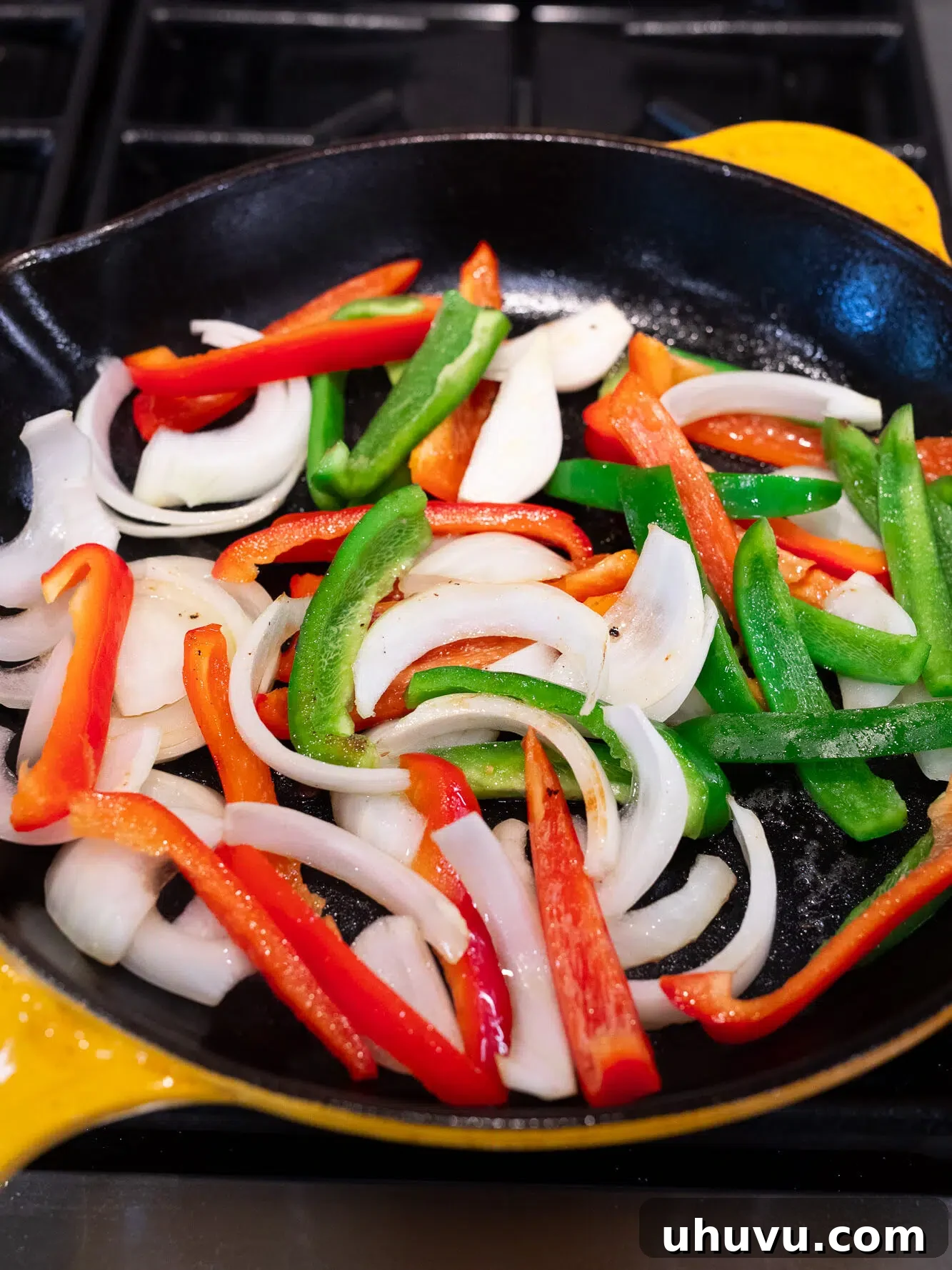 Sautéing bell peppers and onions in a skillet for pepper steak