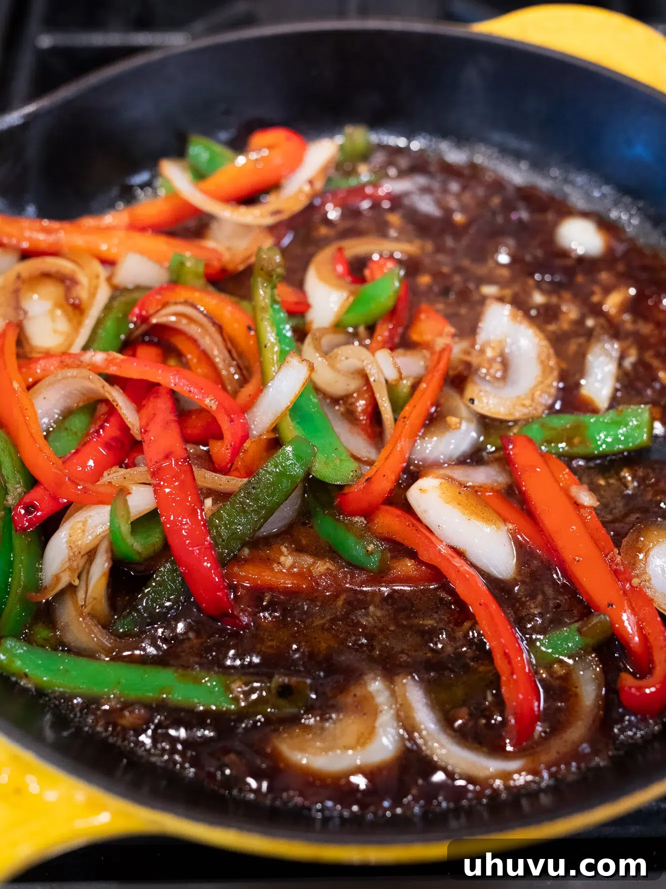 Cooking the stir fry sauce with peppers and onions in a skillet