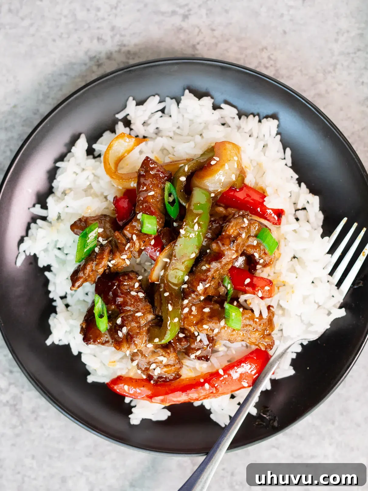 Pepper steak stir fry served over rice on a plate