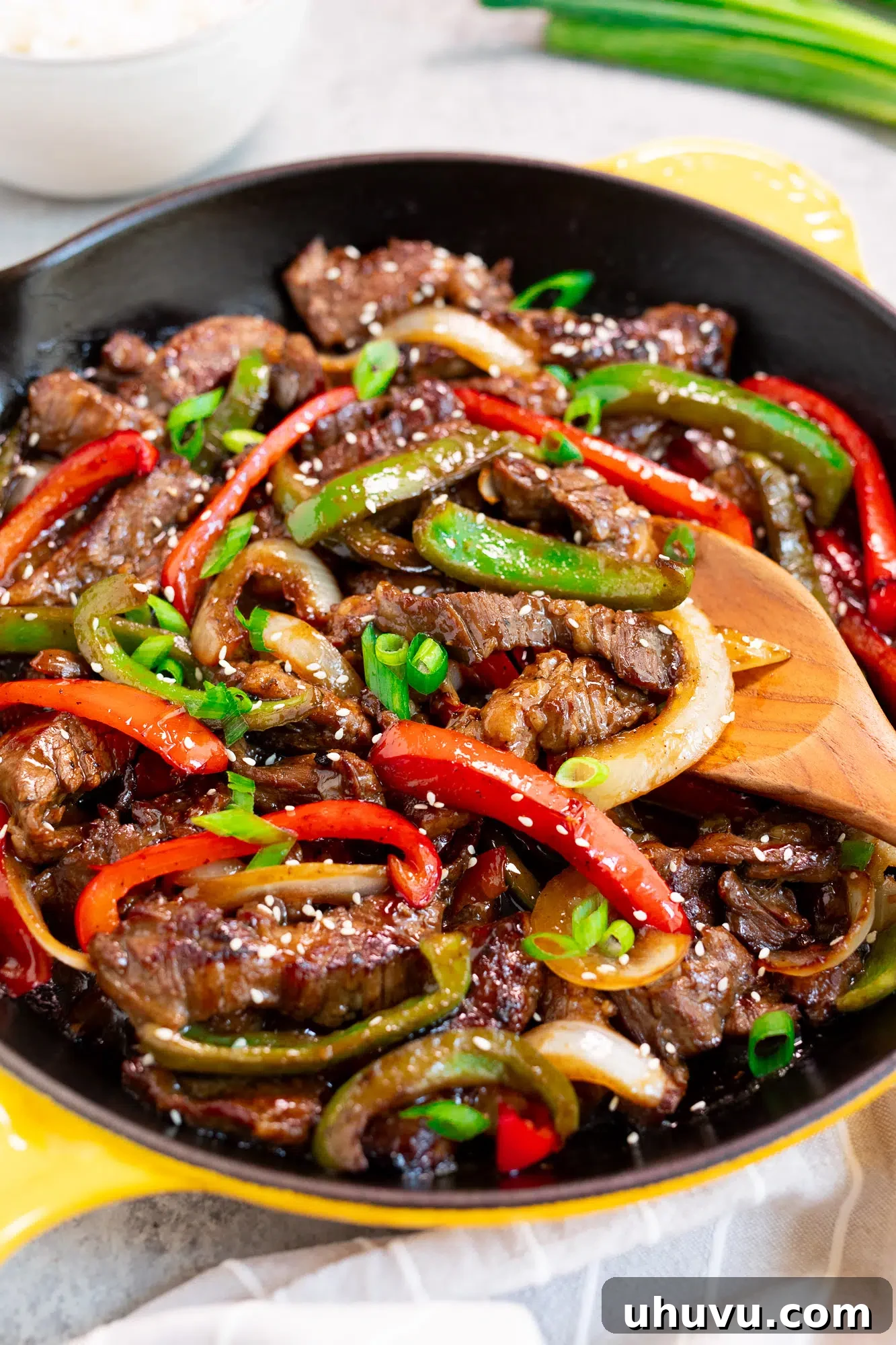 Flank steak, peppers, and onions stir-frying in a large skillet