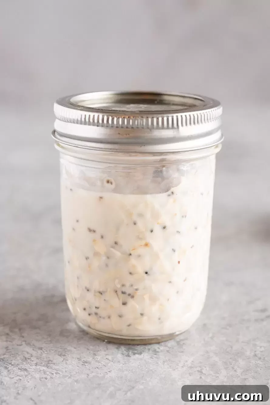 A glass jar containing mixed overnight oats, sealed securely with its lid and placed in a refrigerator.