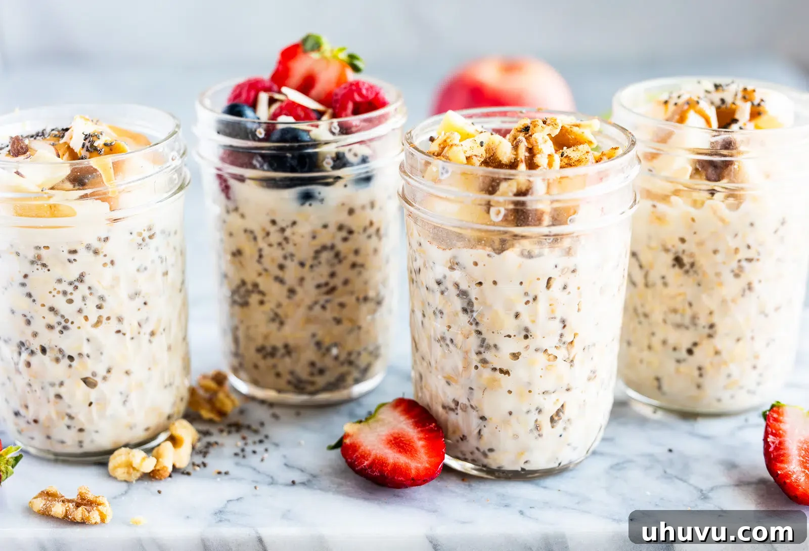Four small glass jars showcasing various make-ahead overnight oats recipes, each topped distinctly with fresh fruits and nuts, perfect as quick and healthy grab-and-go breakfasts for busy mornings.