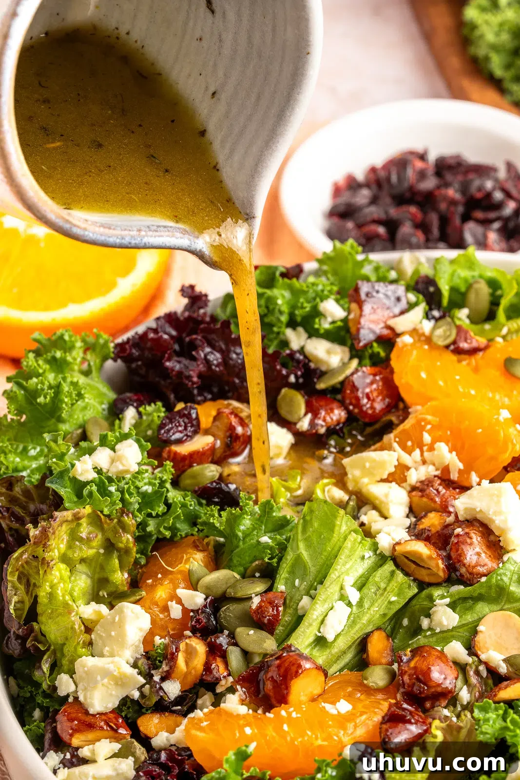 Dressing a vibrant citrus winter salad with red wine vinaigrette, showing a drizzle over the ingredients in a white bowl
