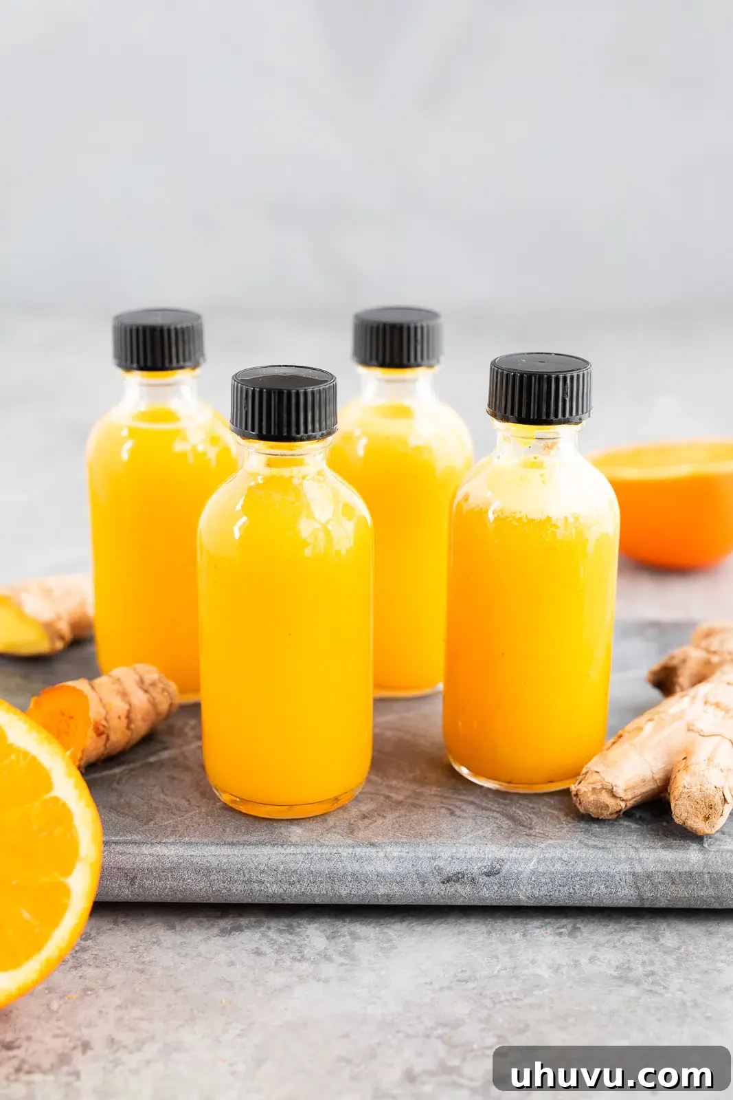 Bottles of homemade ginger turmeric shots made with fresh ginger, turmeric, and citrus