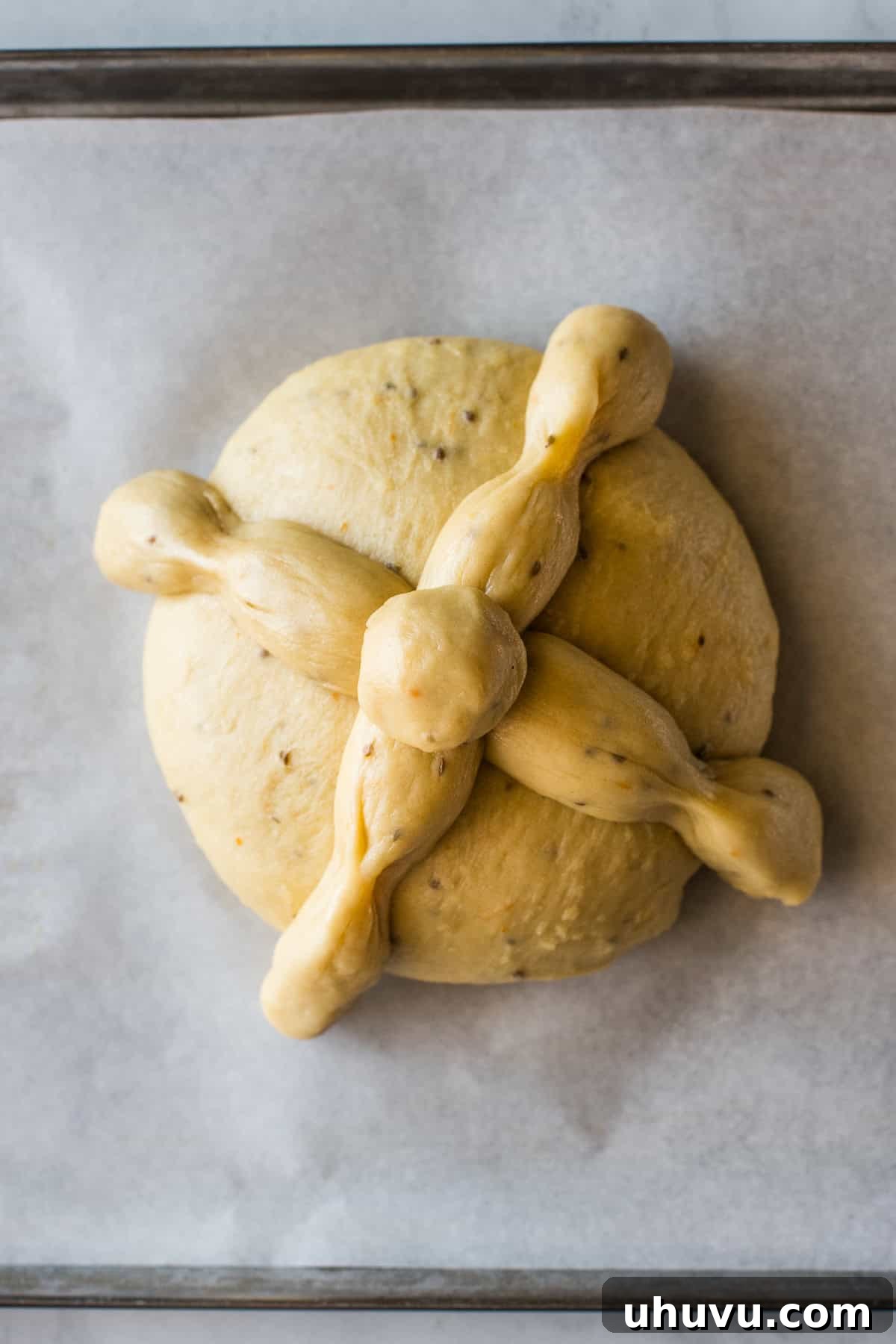 Spirits' Sweet Bread 6 Shaped pan de muerto loaves on a baking sheet lined with parchment paper, ready for the oven.