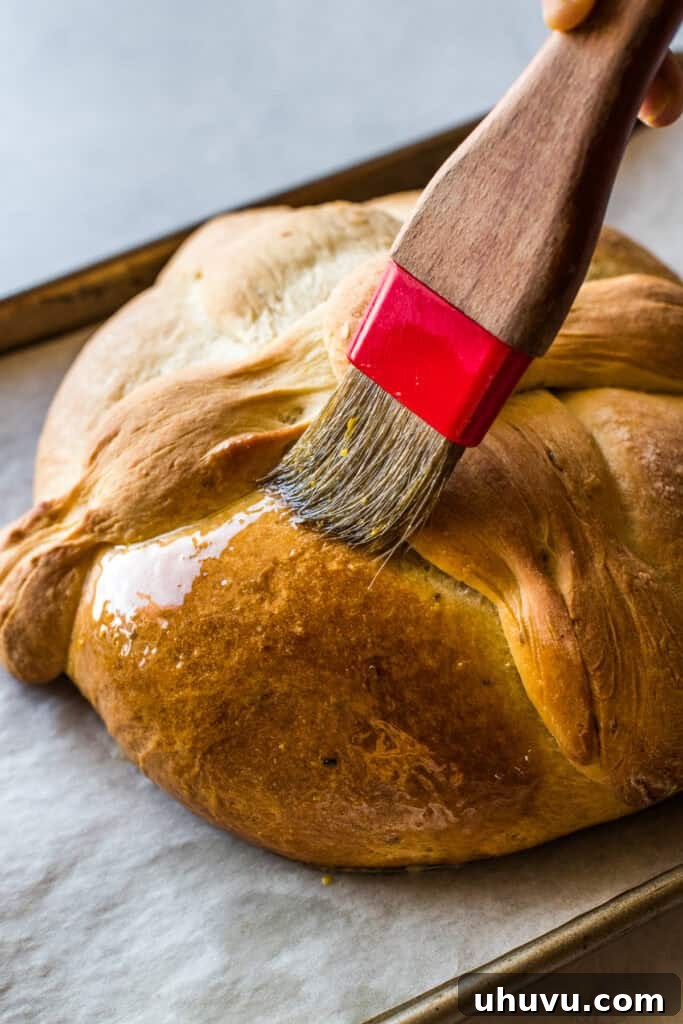 Spirits' Sweet Bread 7 A loaf of pan de muerto being brushed with melted butter and orange zest.