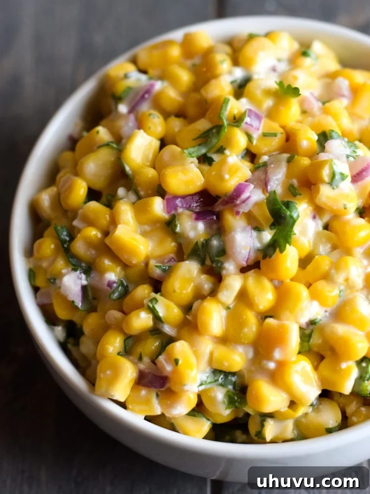 Zesty Elote Tostadas 3 A vibrant close-up of a bowl filled with creamy Mexican street corn mix, featuring bright yellow corn kernels, finely diced red onions, fresh green cilantro, and a generous dollop of rich mayonnaise, ready to be spread.