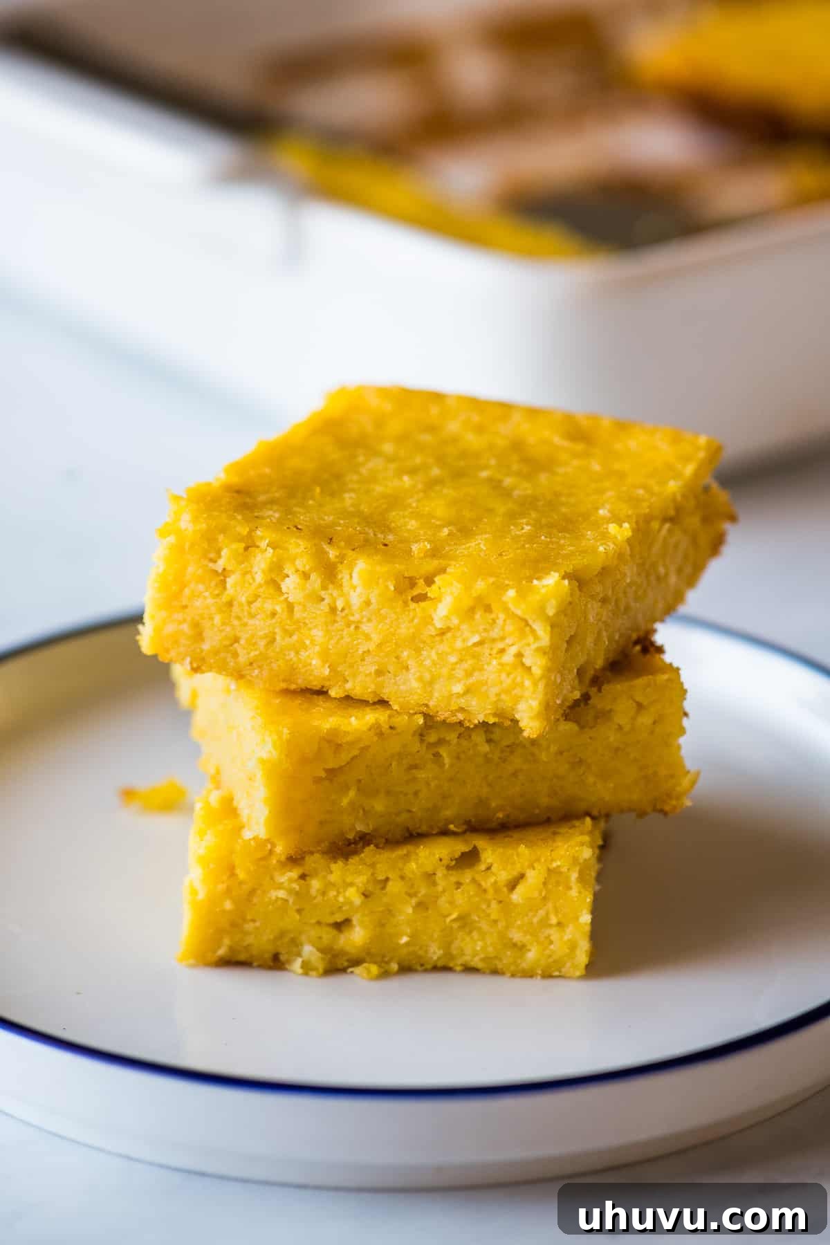 Golden Sweet Corn Cake 2 Three slices of Pan de Elote stacked on top of one another on a plate.