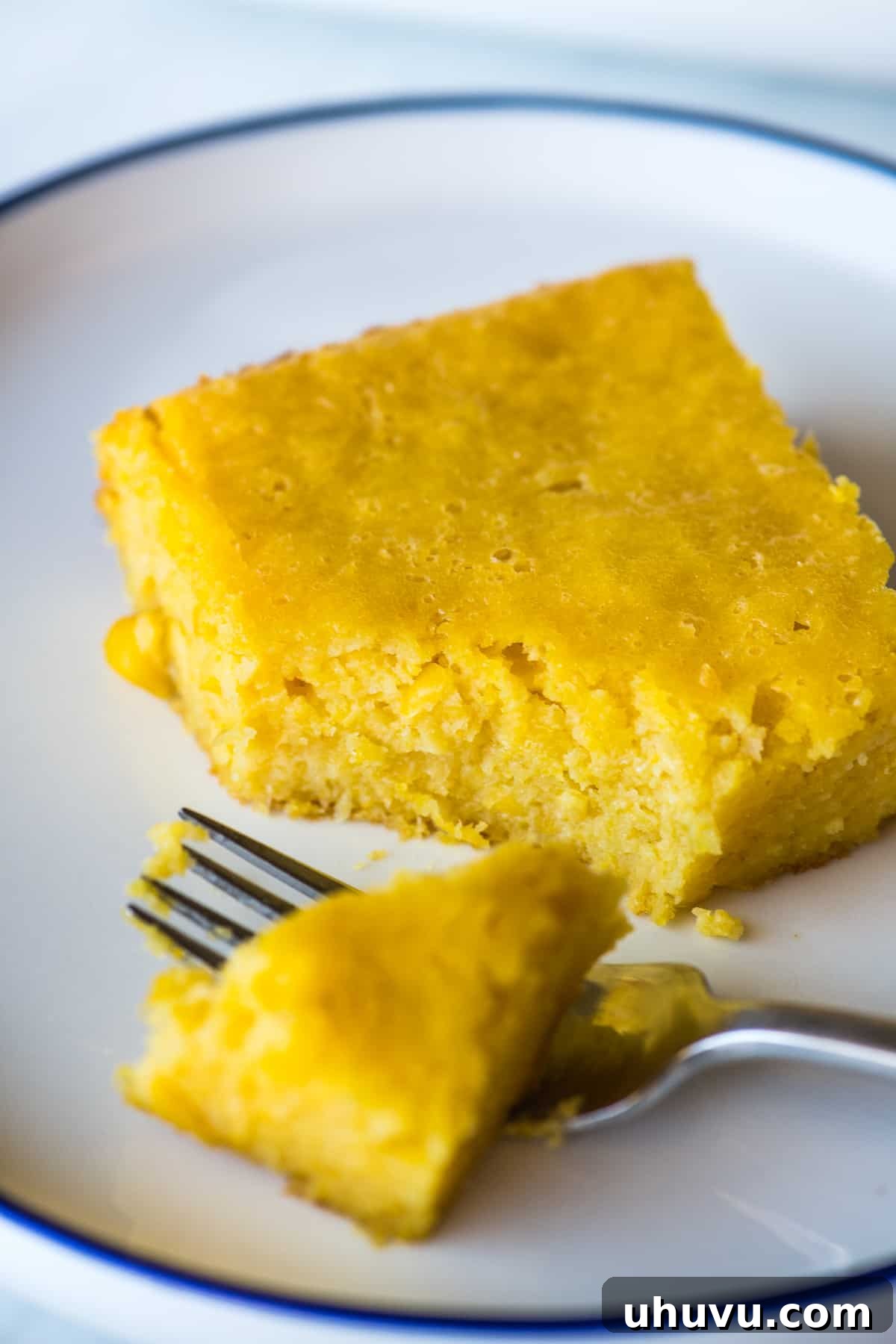 Golden Sweet Corn Cake 7 A slice of pan de elote on a plate with a portion of it on a fork ready to eat.
