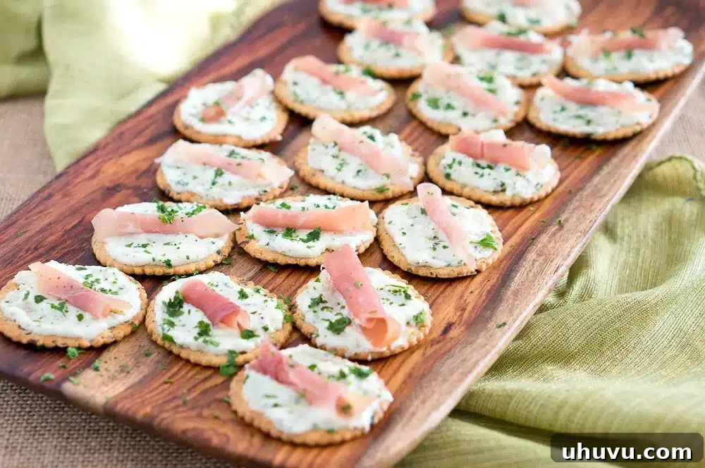 Close-up of Ricotta and Prosciutto Cracker Appetizers on a rustic board