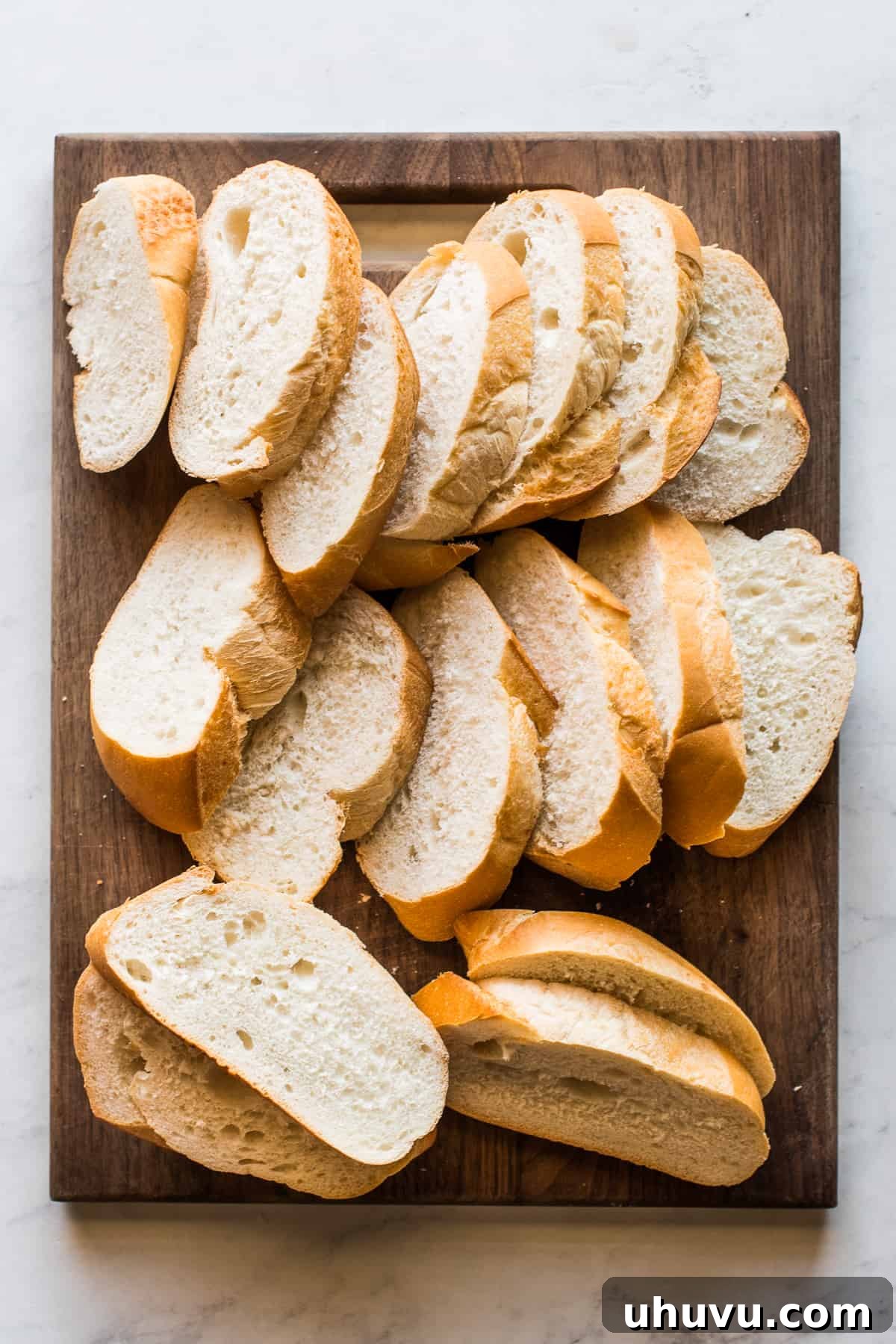 Torrejas Mexican French Toast 3 Slices of dense bolillo bread arranged neatly on a wooden cutting board, ready for making Torrejas.