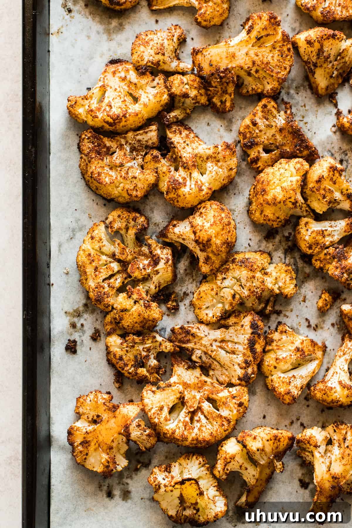 Roasted Cauliflower Taco Revolution 4 Seasoned cauliflower florets spread evenly on a parchment-lined baking sheet, prepared for roasting to be used in delicious cauliflower tacos.