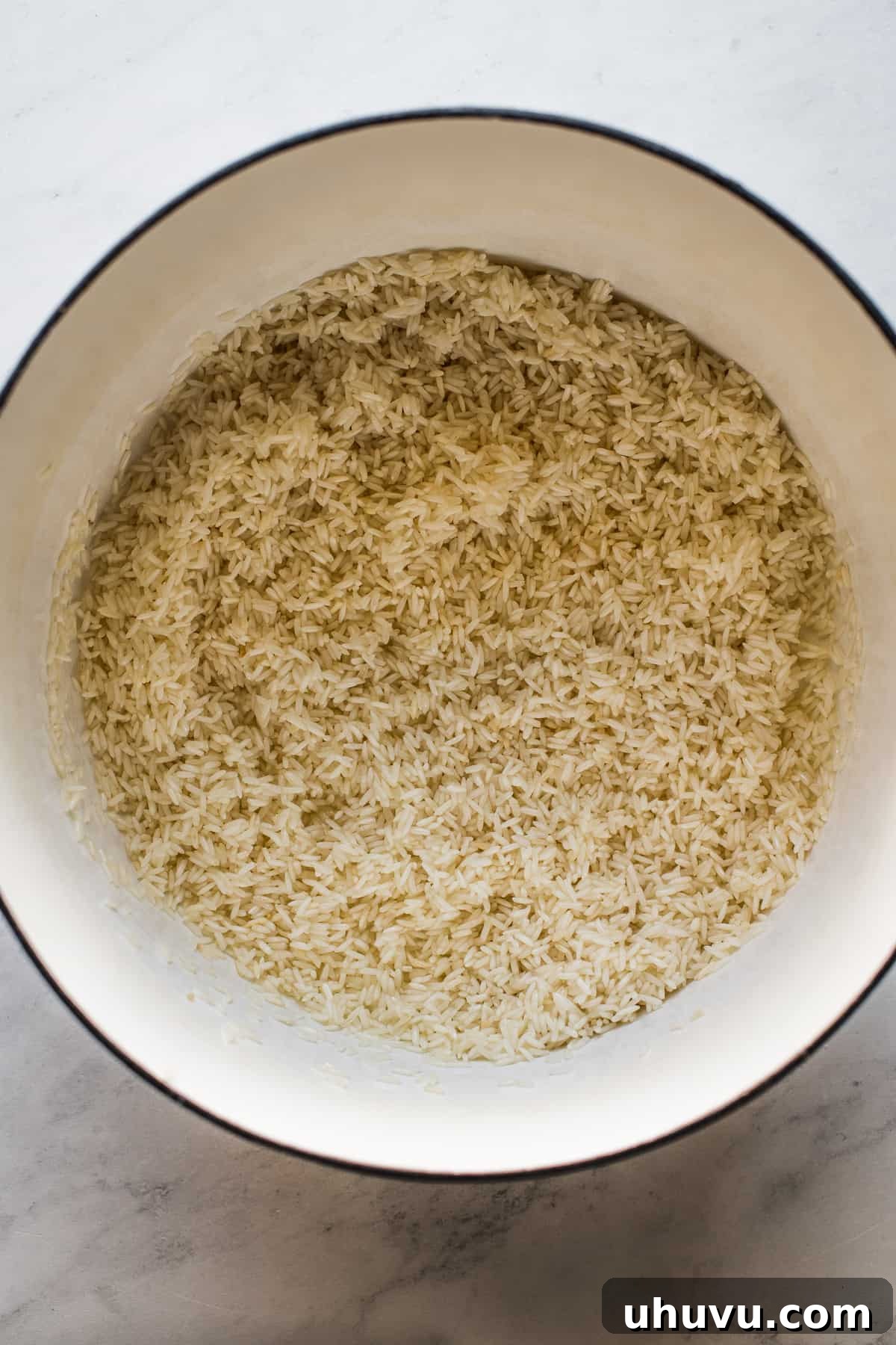 Long grain white rice toasting in a Dutch oven, turning golden brown as it cooks in oil.