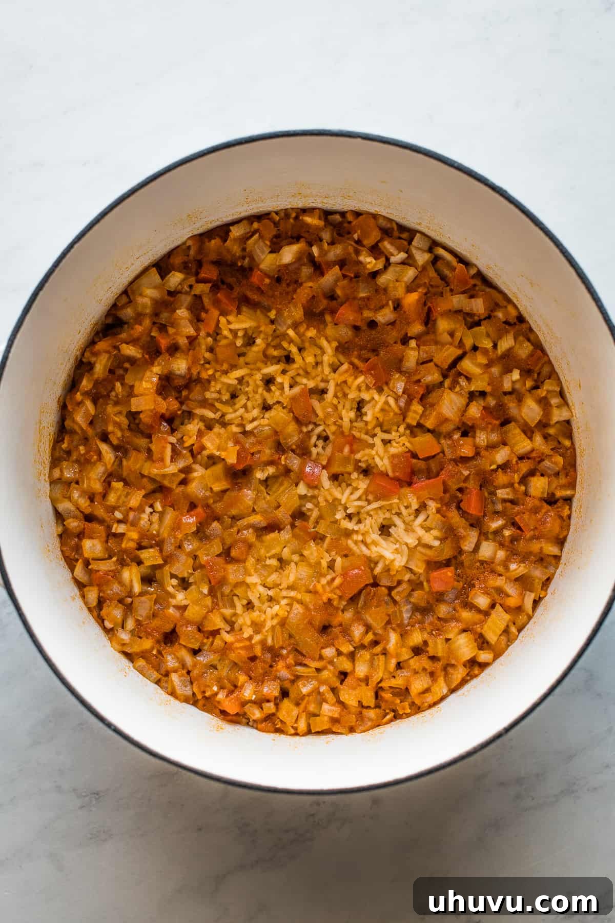 Perfectly cooked Arroz Rojo (Mexican rice) resting in a pot, before being fluffed with a fork and peas are added.
