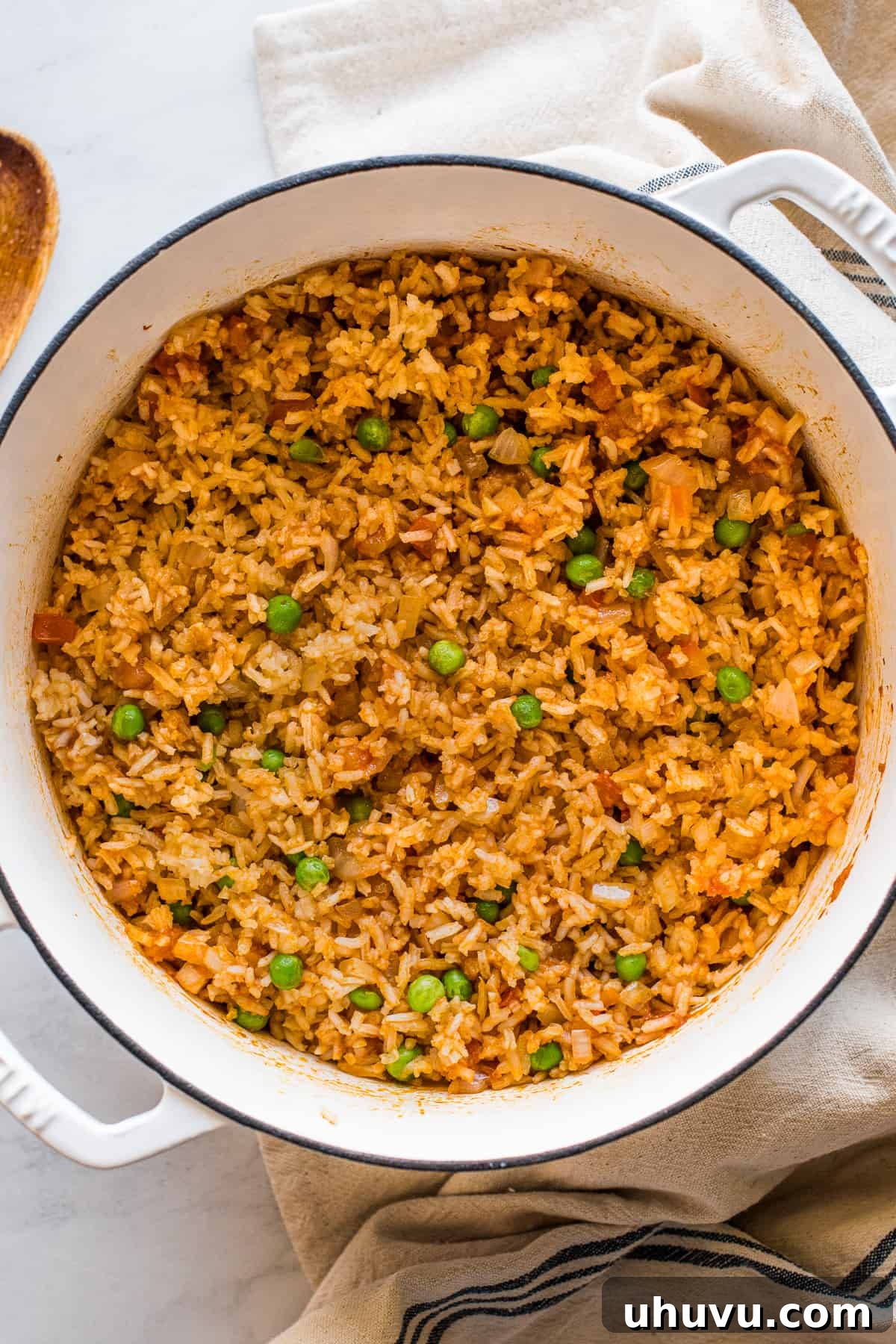 Authentic Mexican rice (Arroz Rojo) served in a large pot, beautifully fluffed with green peas scattered throughout.