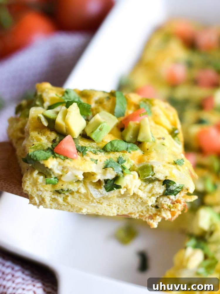 Zesty Salsa Verde Breakfast Frittata 7 An overhead shot showcasing the complete Salsa Verde Breakfast Frittata, garnished lavishly with creamy avocado slices, bright diced tomatoes, and fresh cilantro, promising a delightful culinary experience.