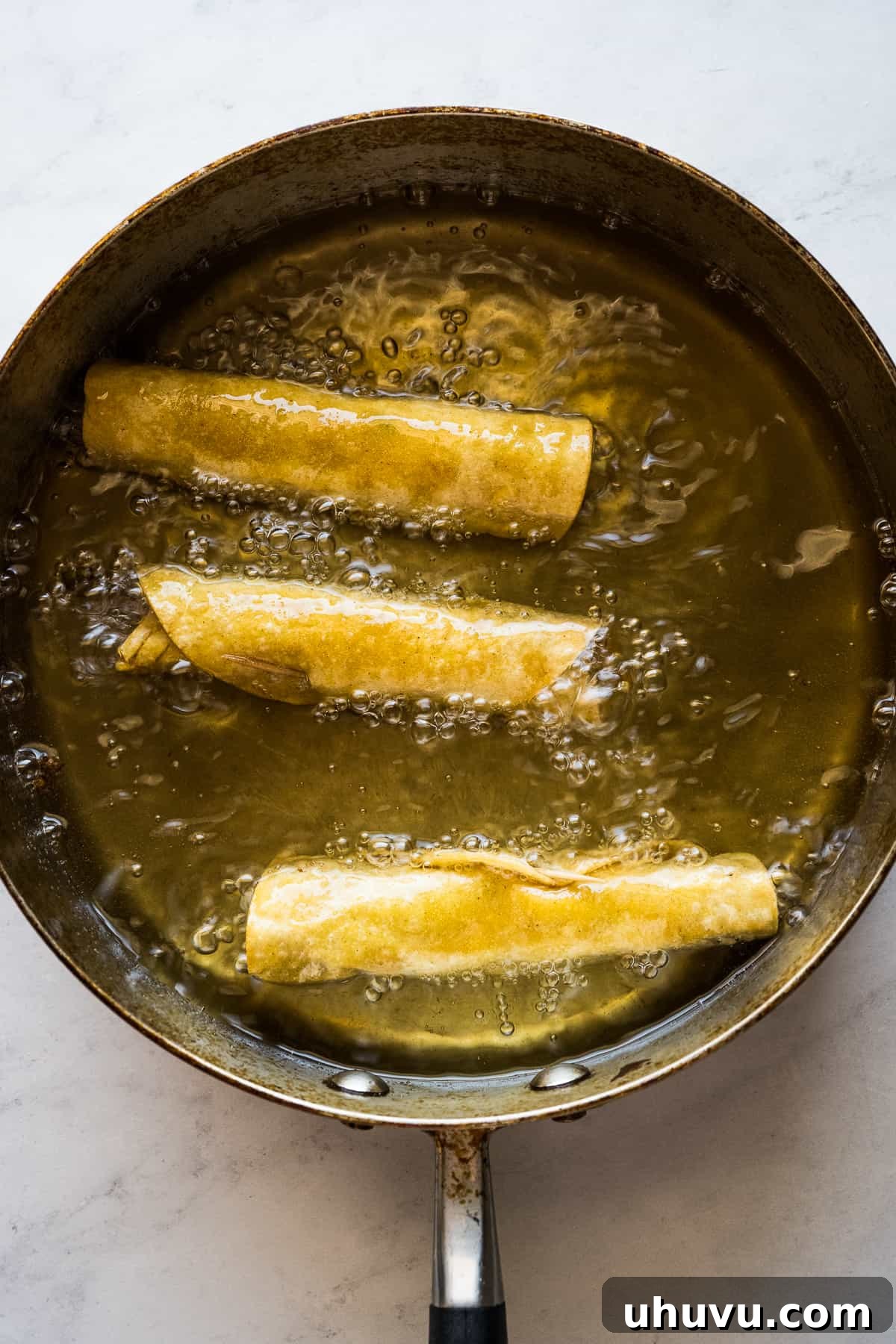 Crispy Rolled Tacos 11 Flautas being fried in oil.