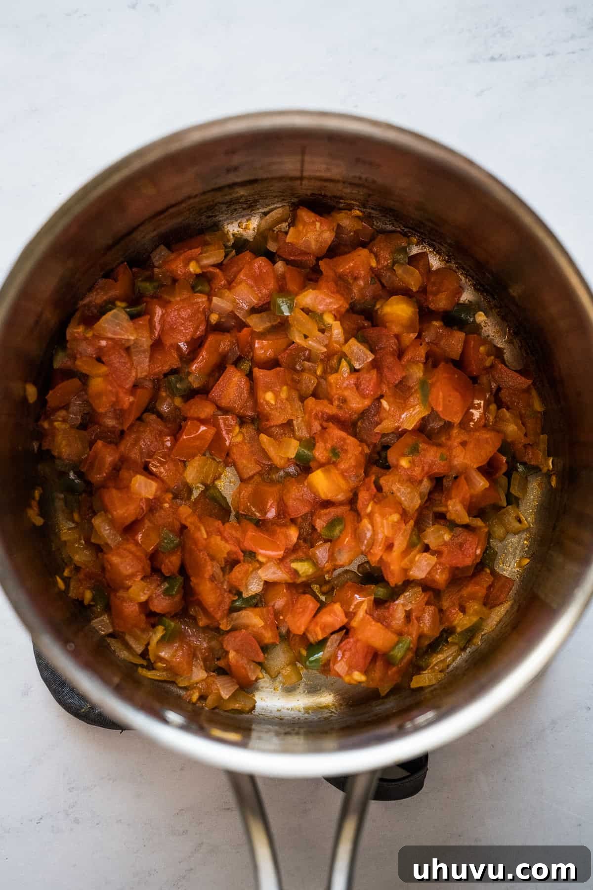 Crispy Rolled Tacos 6 Diced tomatoes, onions, and jalapenos cooking in a small pot.