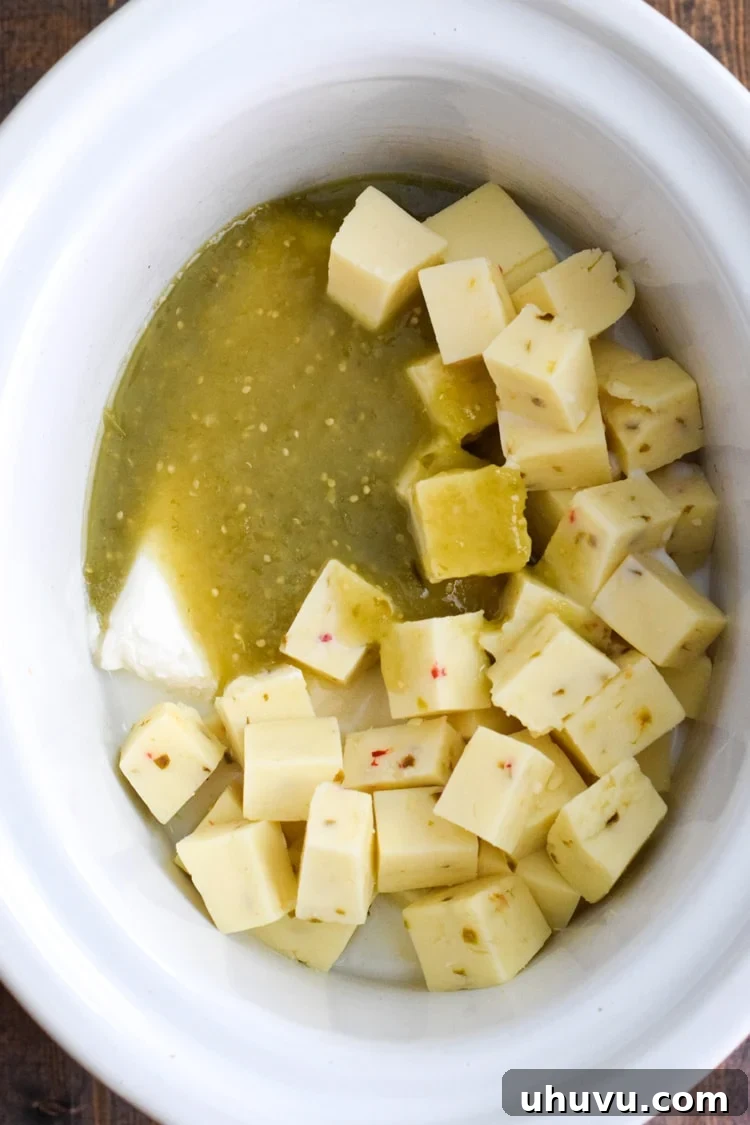 Zesty Green Chili Queso 8 A crockpot filled with salsa verde, cheese cubes, and cream cheese to make salsa verde queso in the slow cooker.