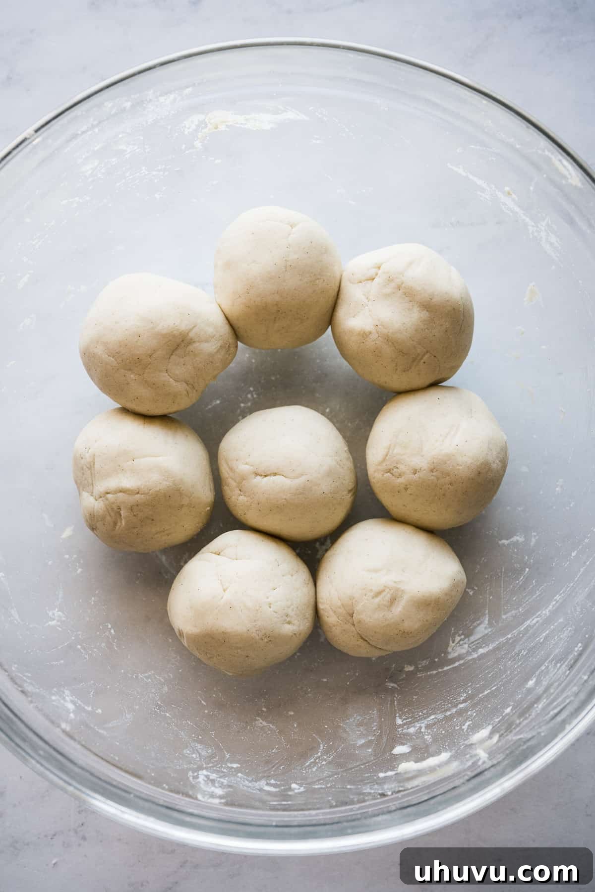 Neatly rolled masa balls resting in a glass bowl, covered and moist, awaiting transformation into delicious huaraches.
