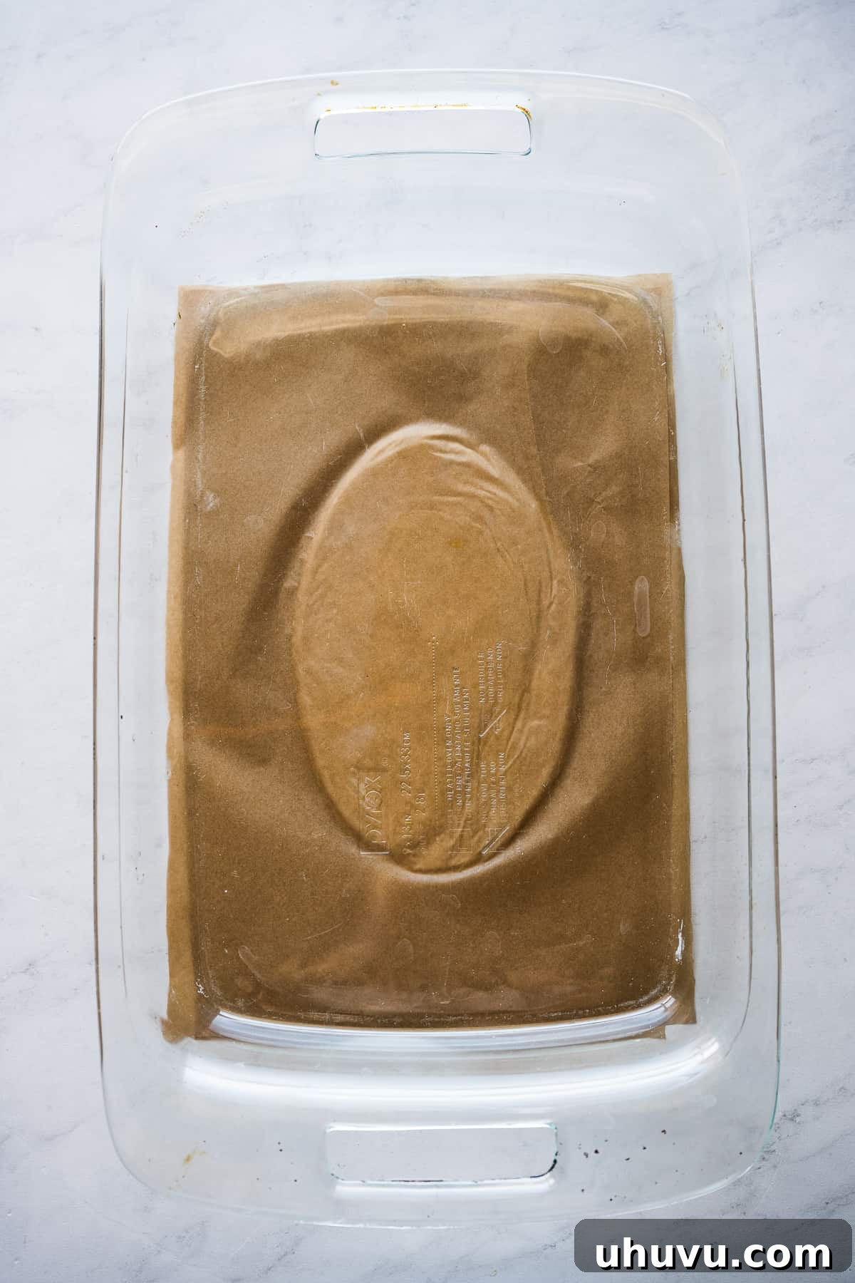 Masa for huaraches being carefully flattened between two sheets of parchment paper, ensuring an even thickness and smooth surface.