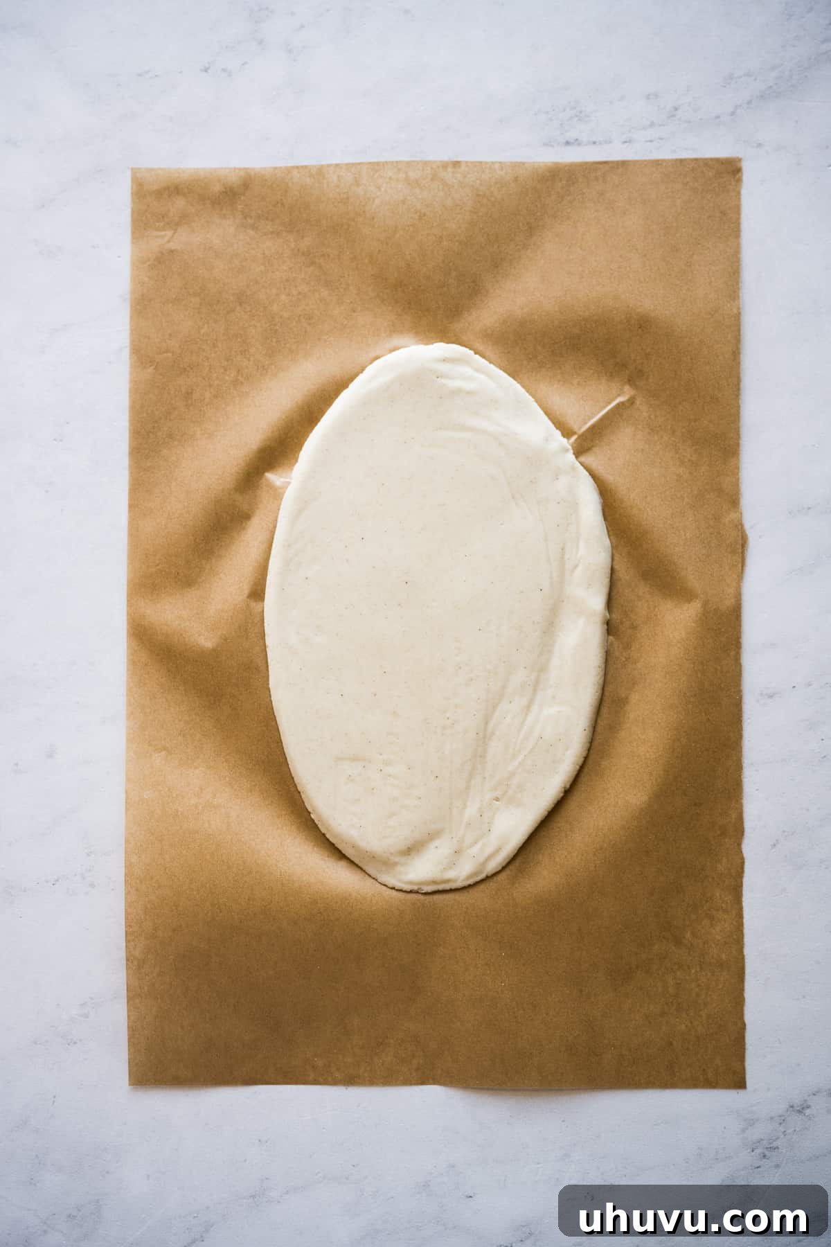 A perfectly flattened piece of masa, shaped into the oblong form characteristic of huaraches, ready for cooking.