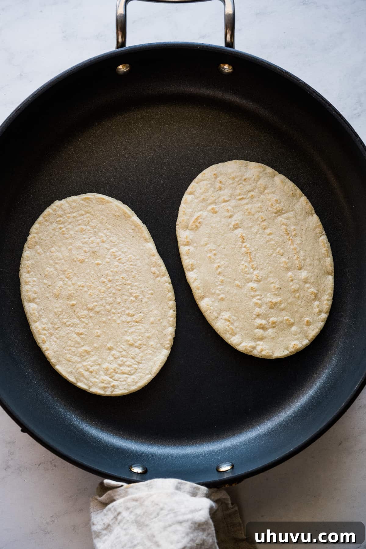 Huaraches being cooked on a hot skillet, showing the beginning stages of browning and crisping, creating a delicious masa base.