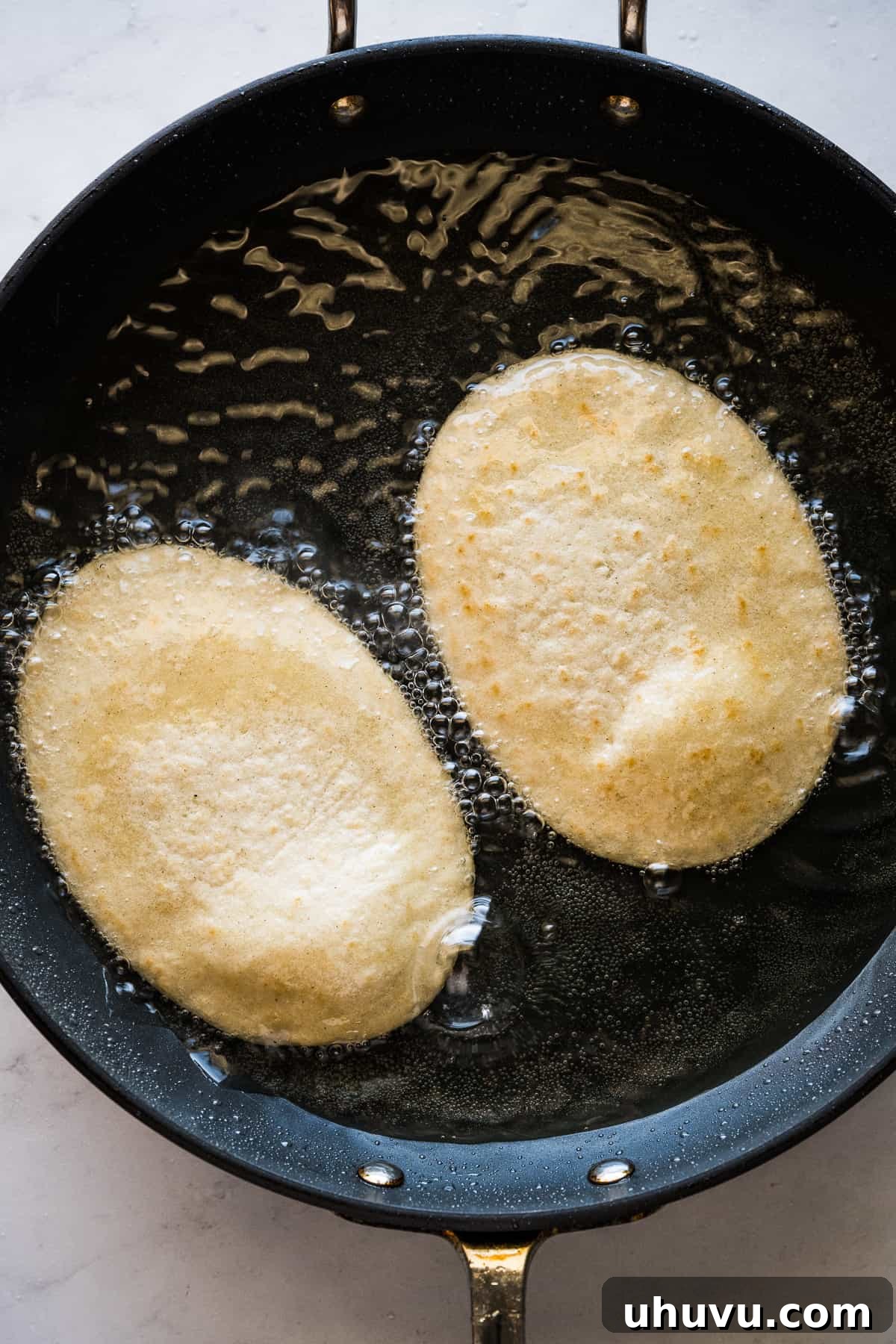 Huaraches being perfectly fried in a skillet filled with hot oil, achieving a golden-brown and crispy texture.