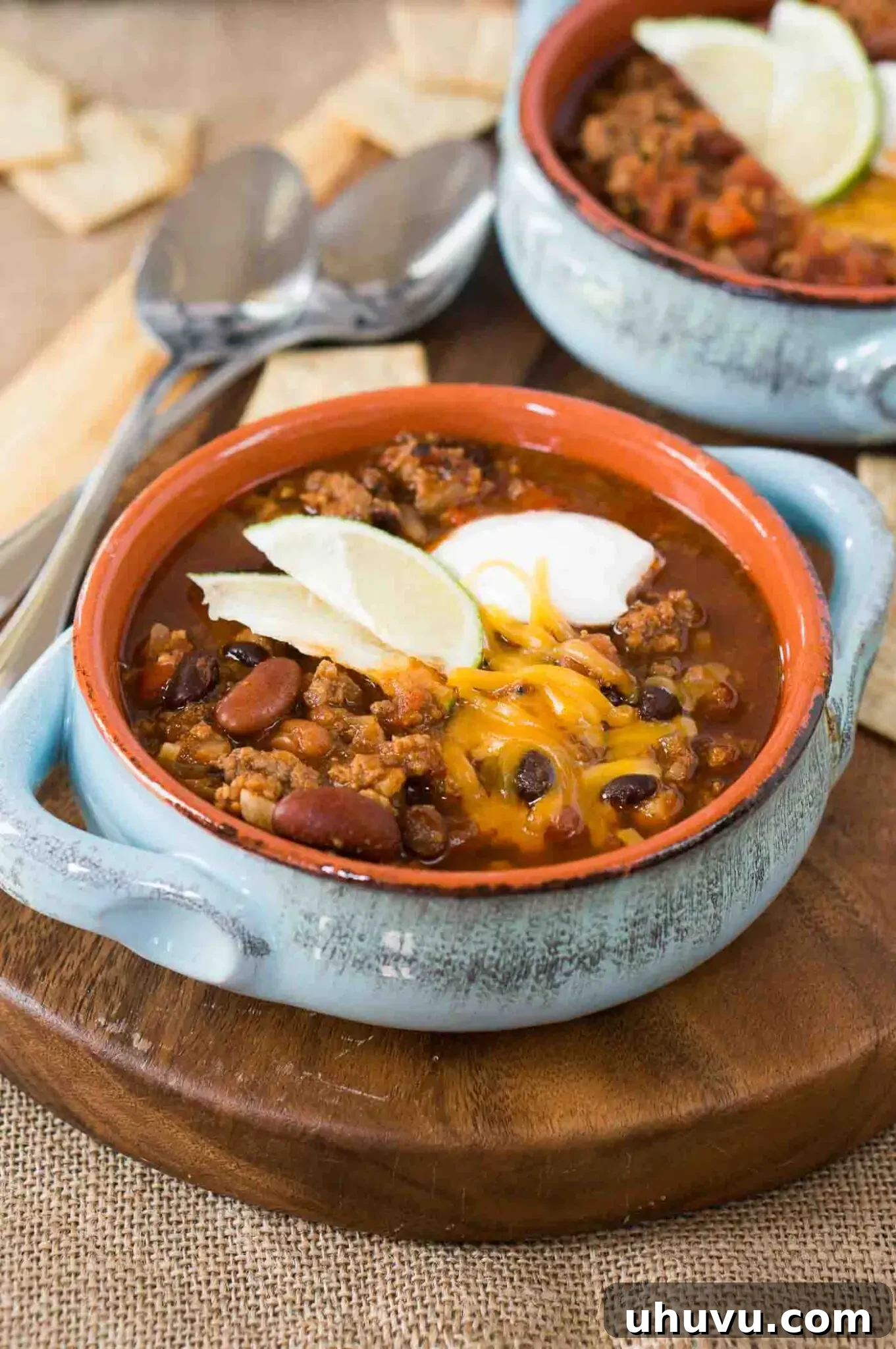 Hearty Instant Pot Chili 8 chili topped with sour cream, cheese and lime slices in a bowl