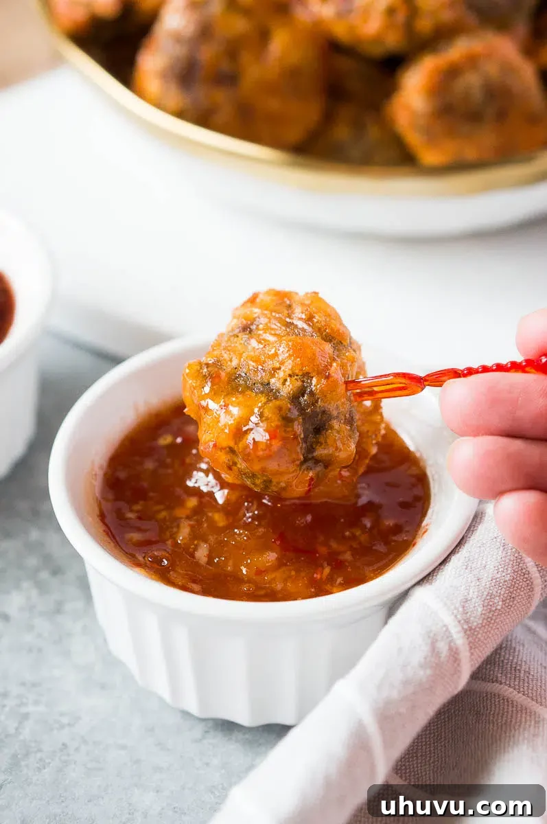 Dipping a sausage ball into a vibrant apricot chili dip