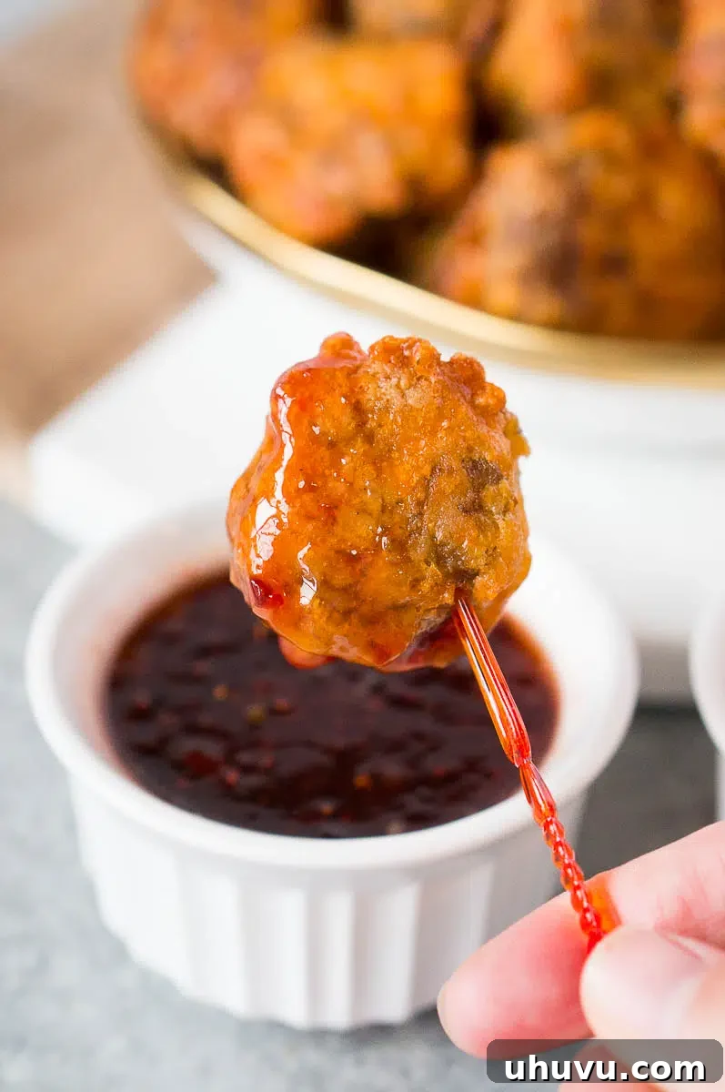Dipping a sausage ball into a savory raspberry chili dip