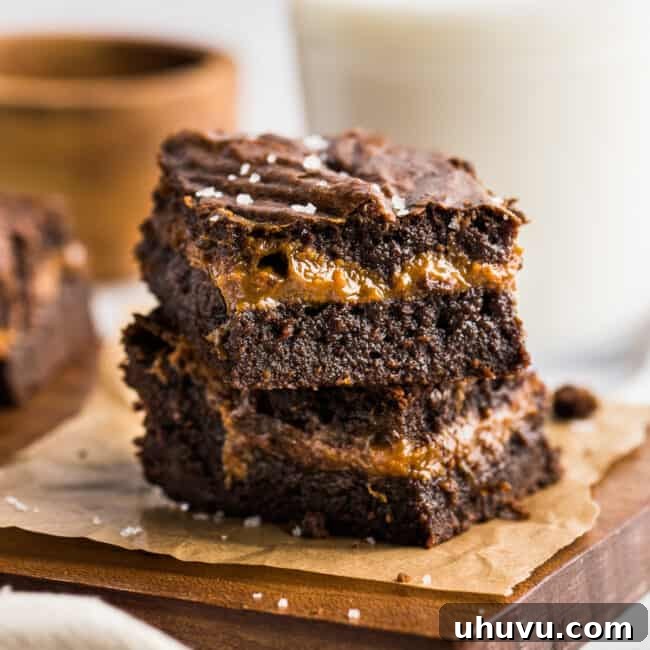Dulce de Leche Brownies stacked on top of one another to showcase the layer of dulce de leche in the middle.