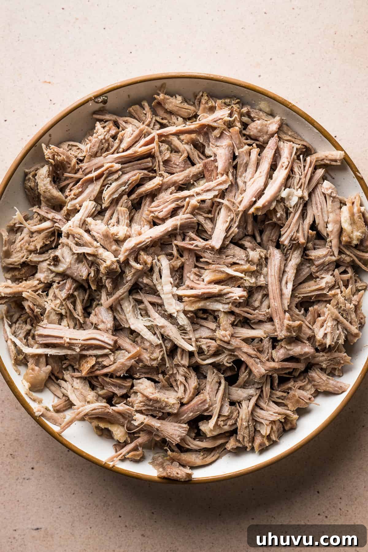 Perfectly shredded, tender pork pieces resting on a plate, ready to be returned to the Pozole Blanco broth.