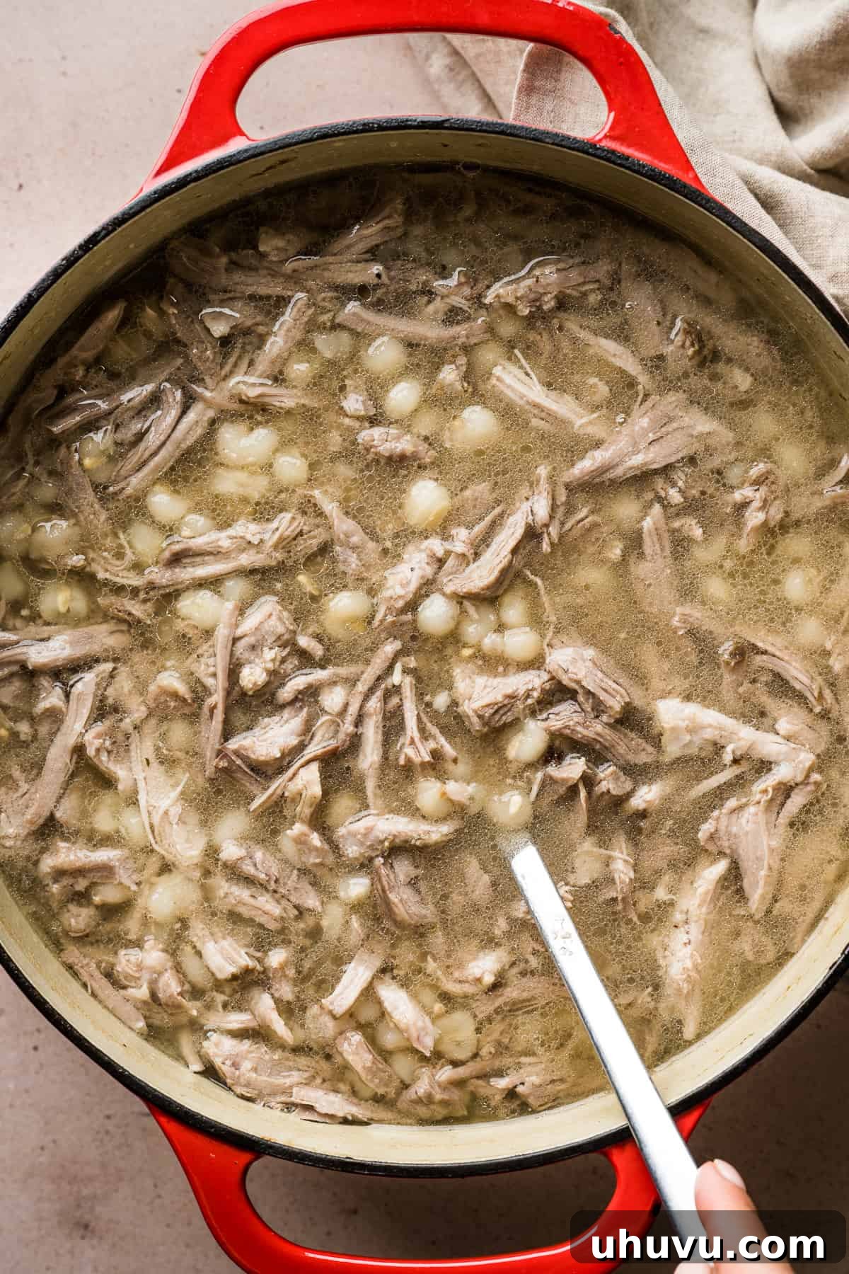 A large pot of rich and hearty Pozole Blanco, filled with tender pork and hominy in a clear, flavorful broth, ready to be served.