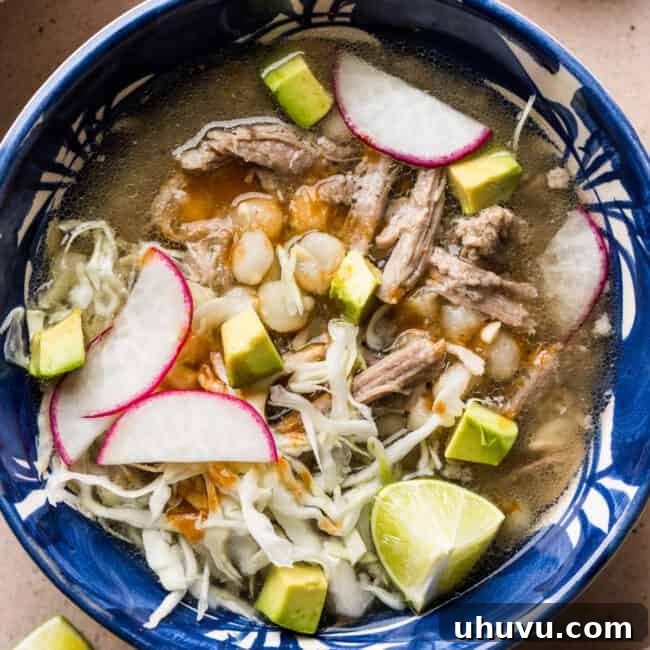 Pozole blanco in a bowl topped with avocado, radishes, and thinly sliced cabbage.