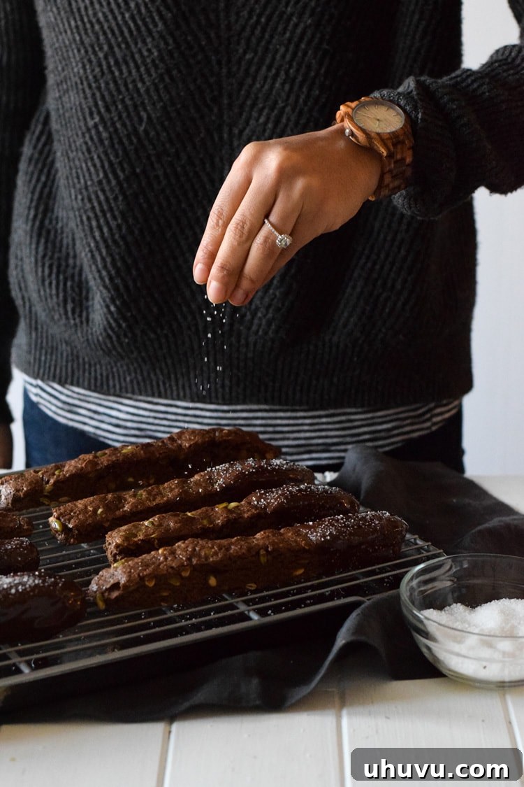 Crisp Cocoa Pepita Biscotti 3 Close-up of freshly baked Mexican Chocolate Pumpkin Seed Biscotti, generously dipped in rich milk chocolate and garnished with coarse sea salt, next to a JORD Wood Watch, symbolizing holiday gifting.