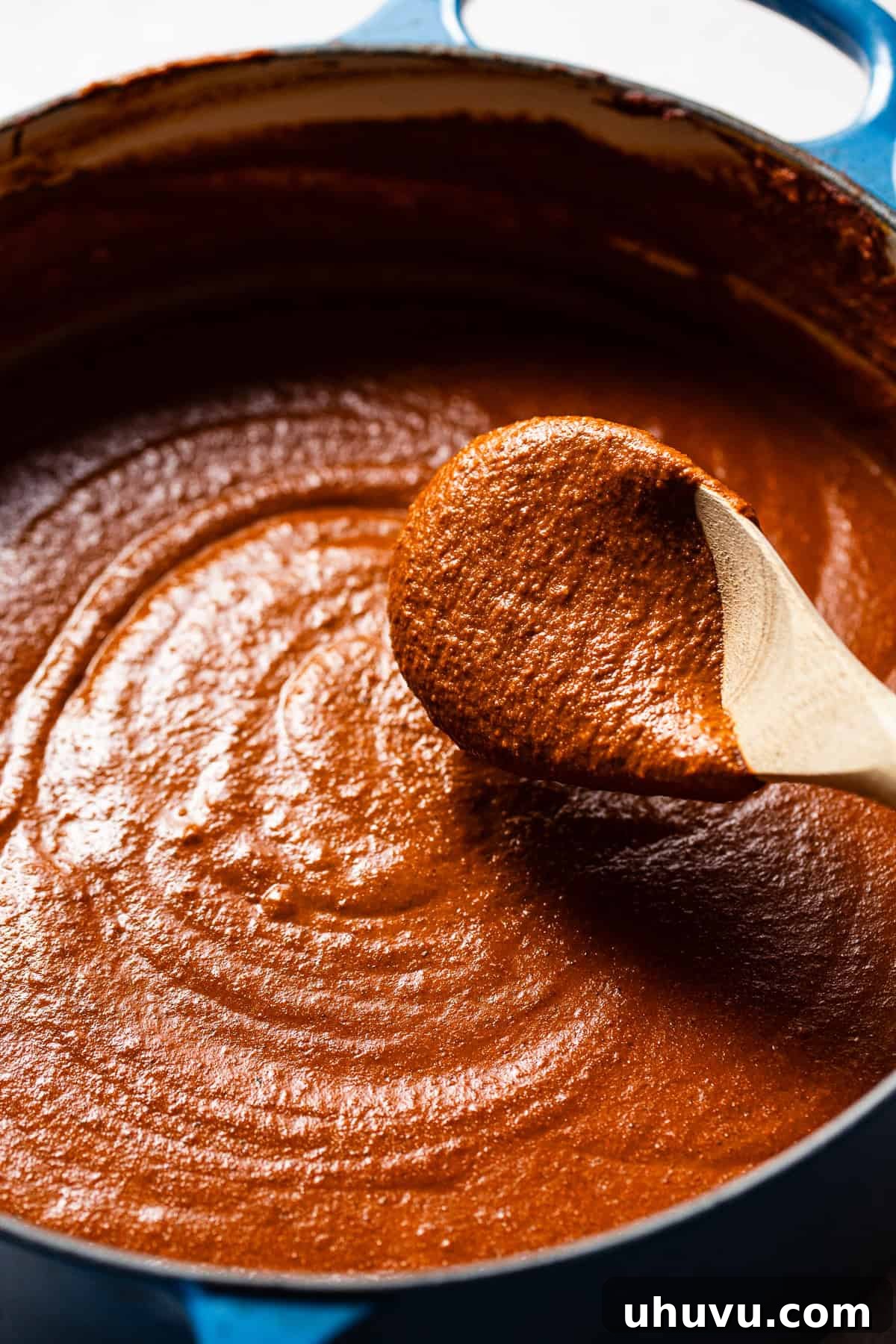 Classic Mexican Mole Poblano Sauce 9 A wooden spoon scooping up the finished Mole Poblano sauce, showcasing its smooth texture and deep brown color.