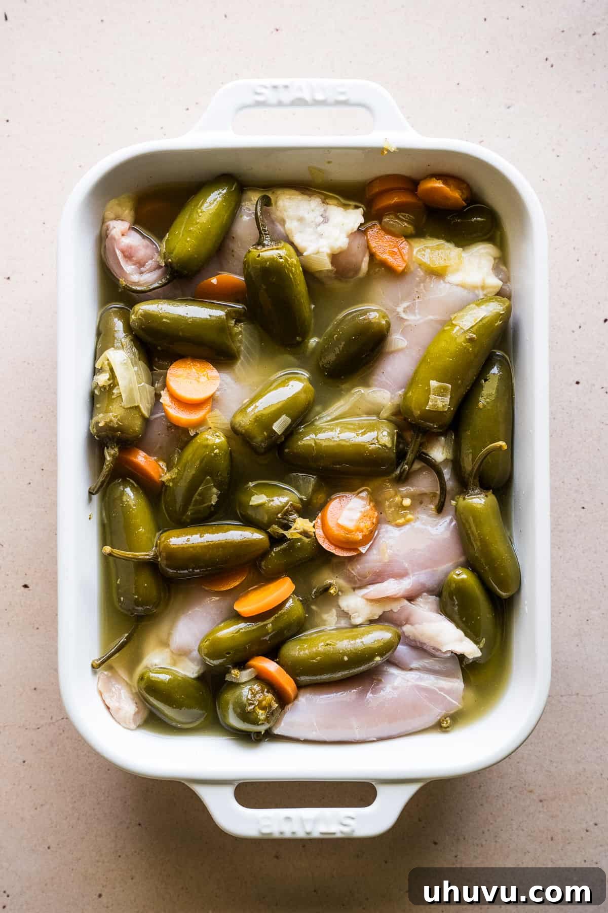 Your Secret to Perfectly Flavorful Chicken 4 Chicken marinated in pickled jalapeños, ready for cooking, showing the vibrant color of the marinade.