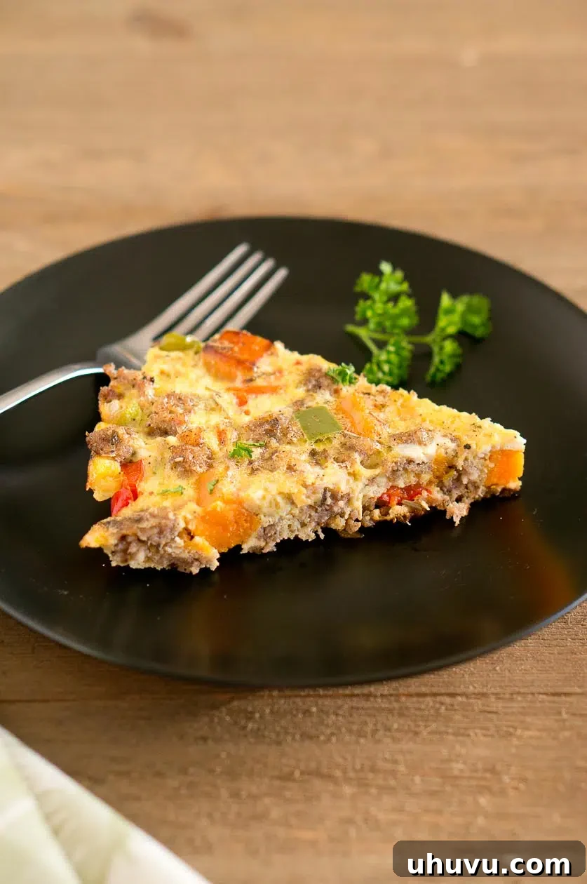 Close-up of a slice of Sweet Potato Sausage Frittata recipe, showing chunks of sweet potato and savory sausage