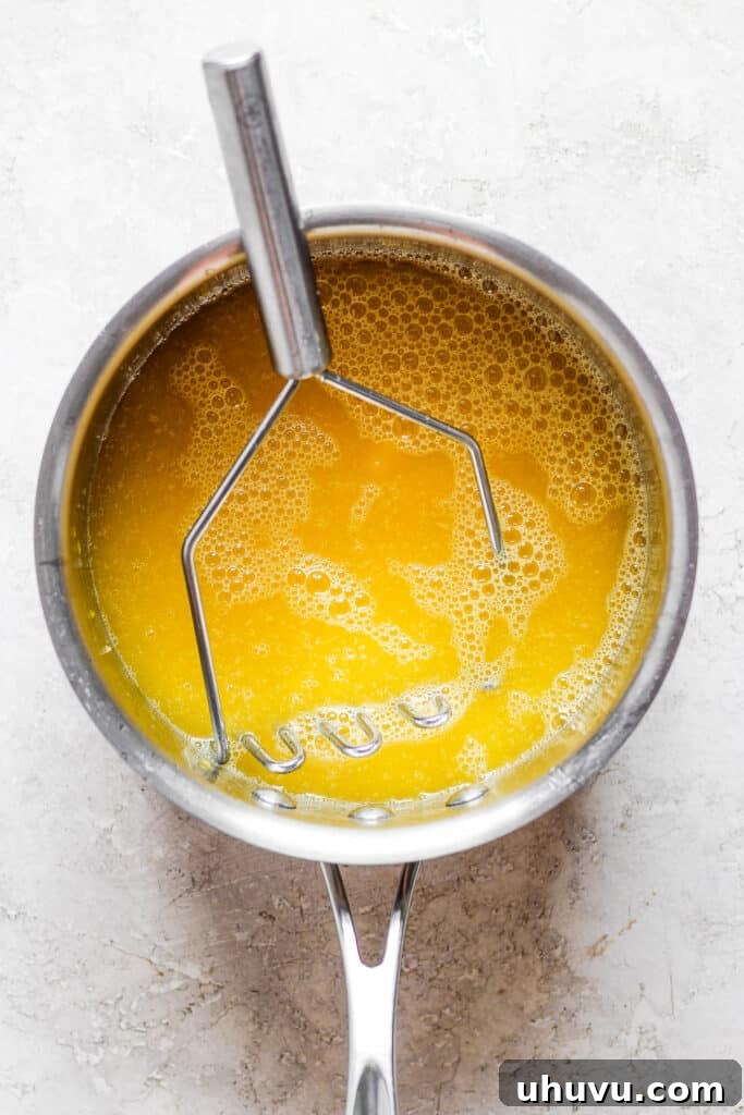Rich, golden mango syrup in a saucepan after being cooked and reduced, ready to be cooled and used for raspados.